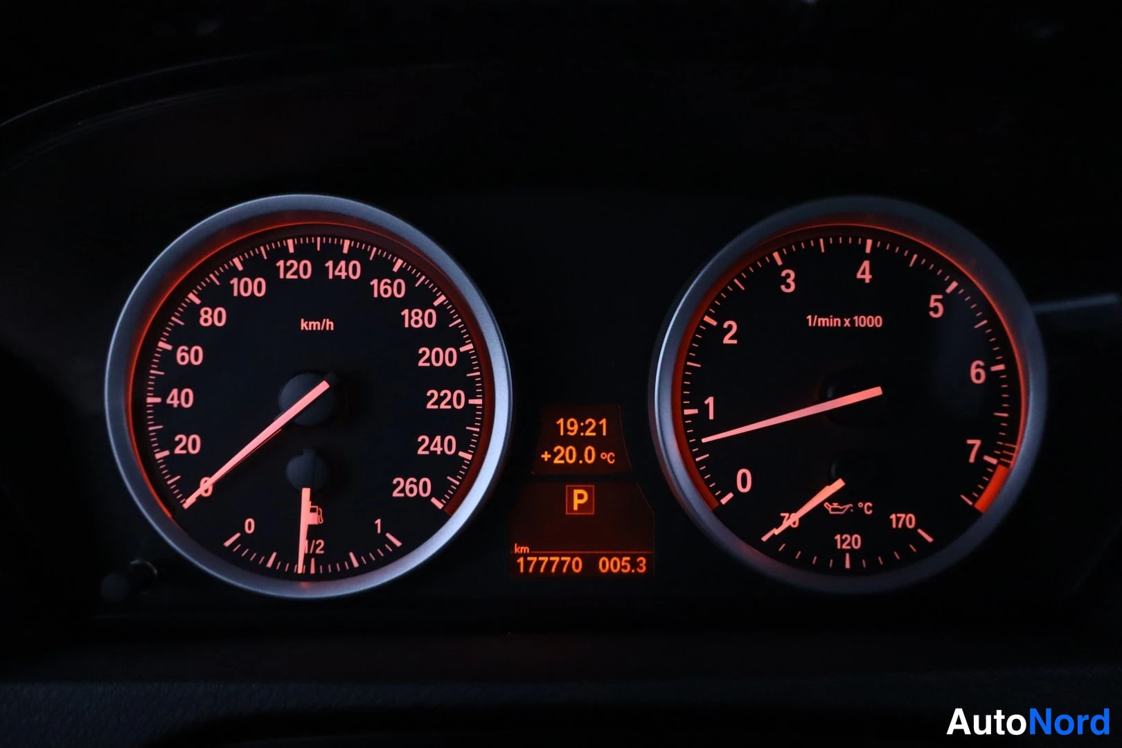 Takaa: Kojeiston mittarit punaisella valaistuna: nopeusmittari ja kierrosmittari, näytössä P, 177770 km, aika 19:21 ja +20,0 °C.