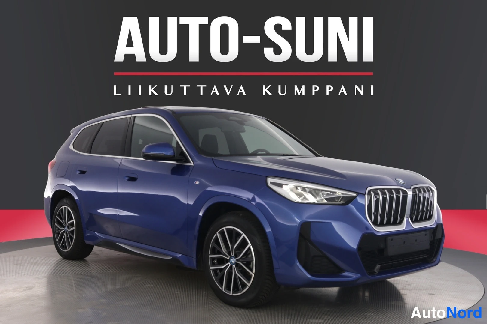 Etuviisto, nokka oikealle: Sininen BMW iX1 -maasturin etukulmanäkyvissä:
