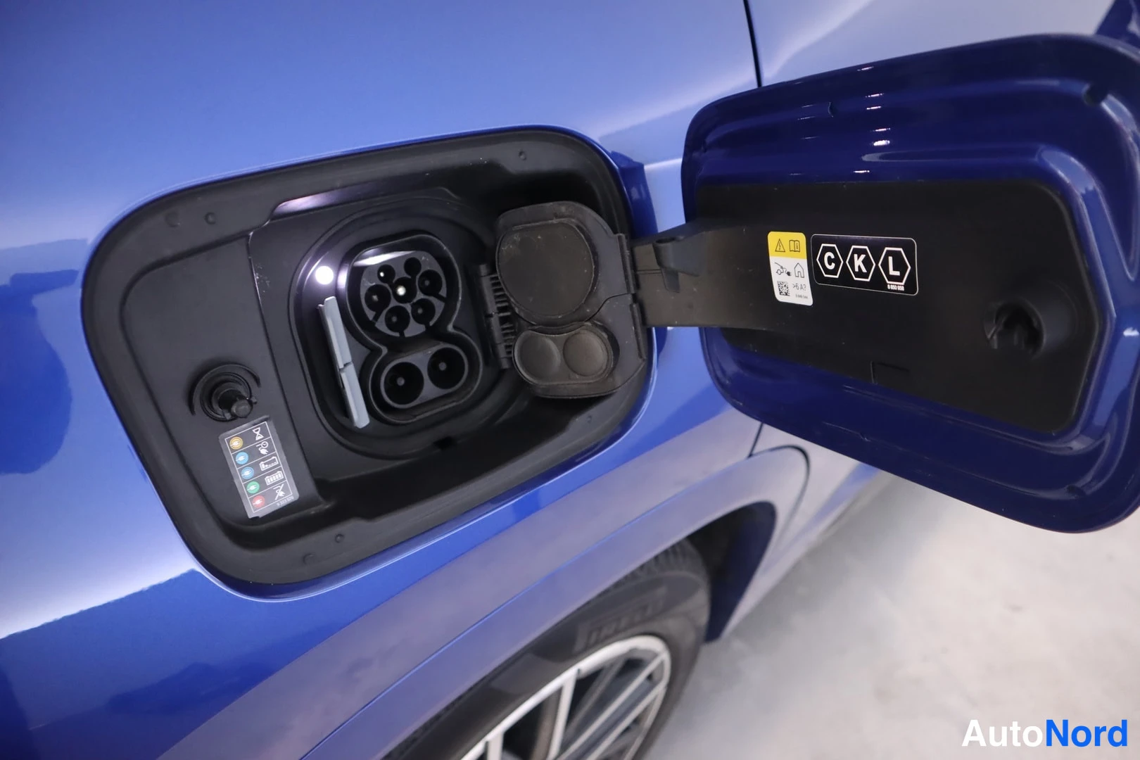 Yksityiskohta: Sinisen auton avattu sähköautojen latausportti, jossa Combo- ja määrätty vaihtovirtaliitin sekä latausvaloindikaattorit.