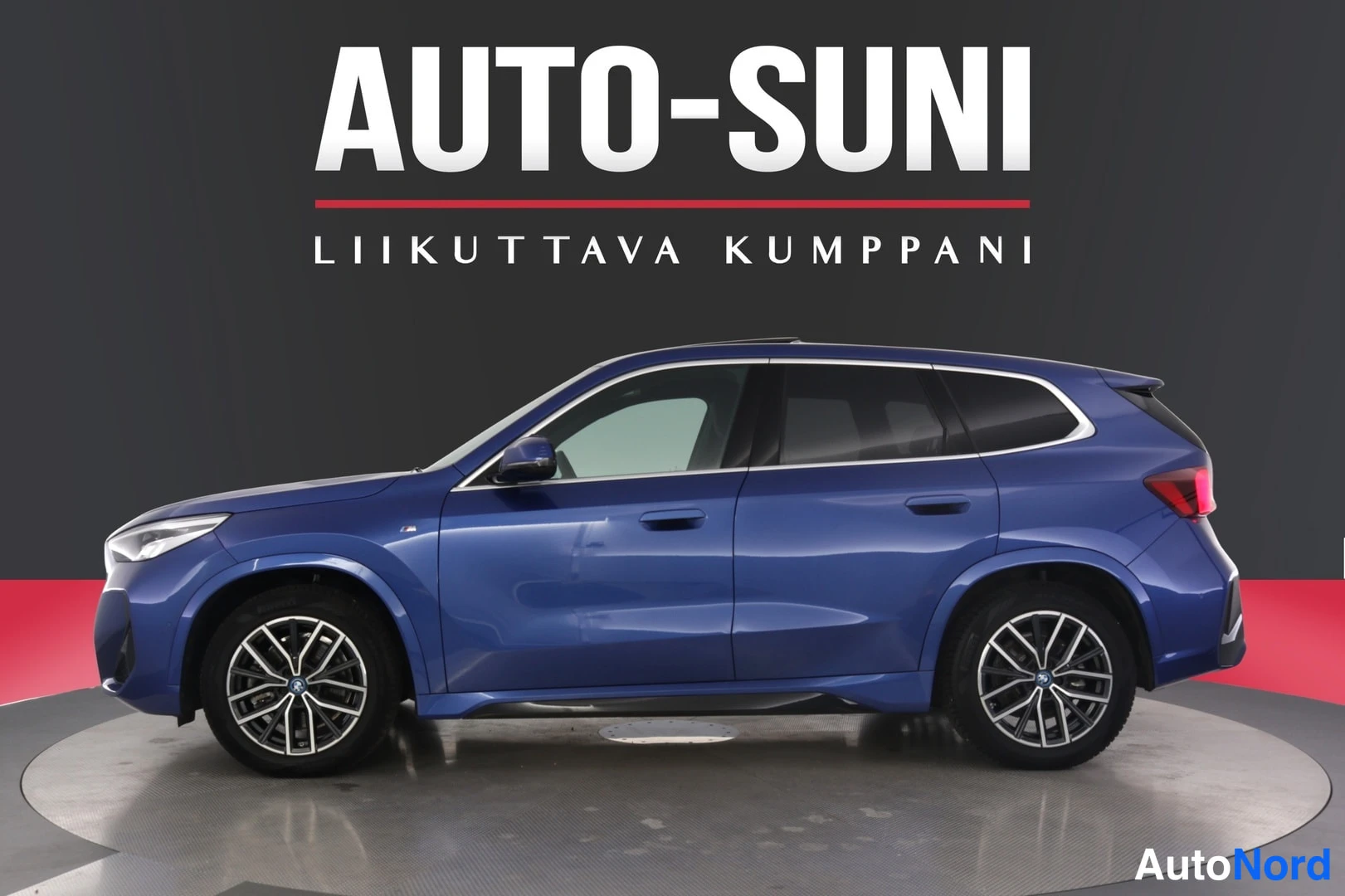 Sivulta: Sivulta kuvattu sininen BMW iX1, keulan etunurkka ja kylki näkyvissä.