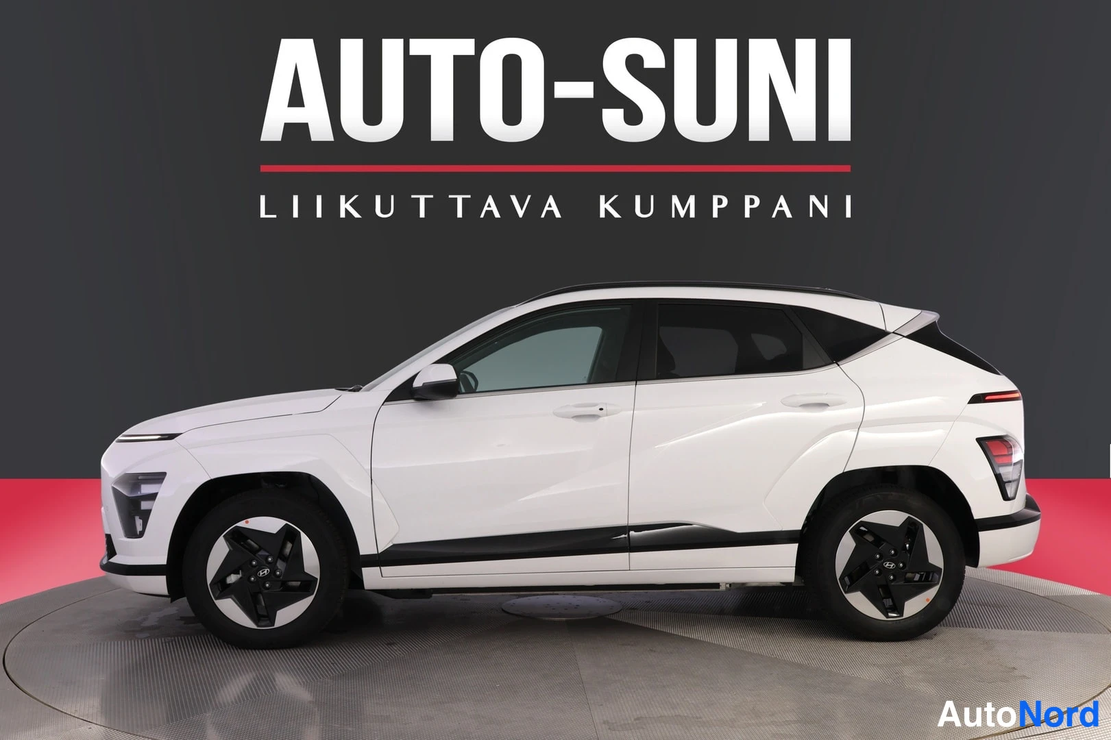 Etuviisto, nokka vasemmalle: Valkoinen Hyundai Kona Electric kolmastaudineuvonnasta, keula vasemmalla, täysi sivuprofiili näkyvissä mustalla kattoon päin viistävällä lasilla.