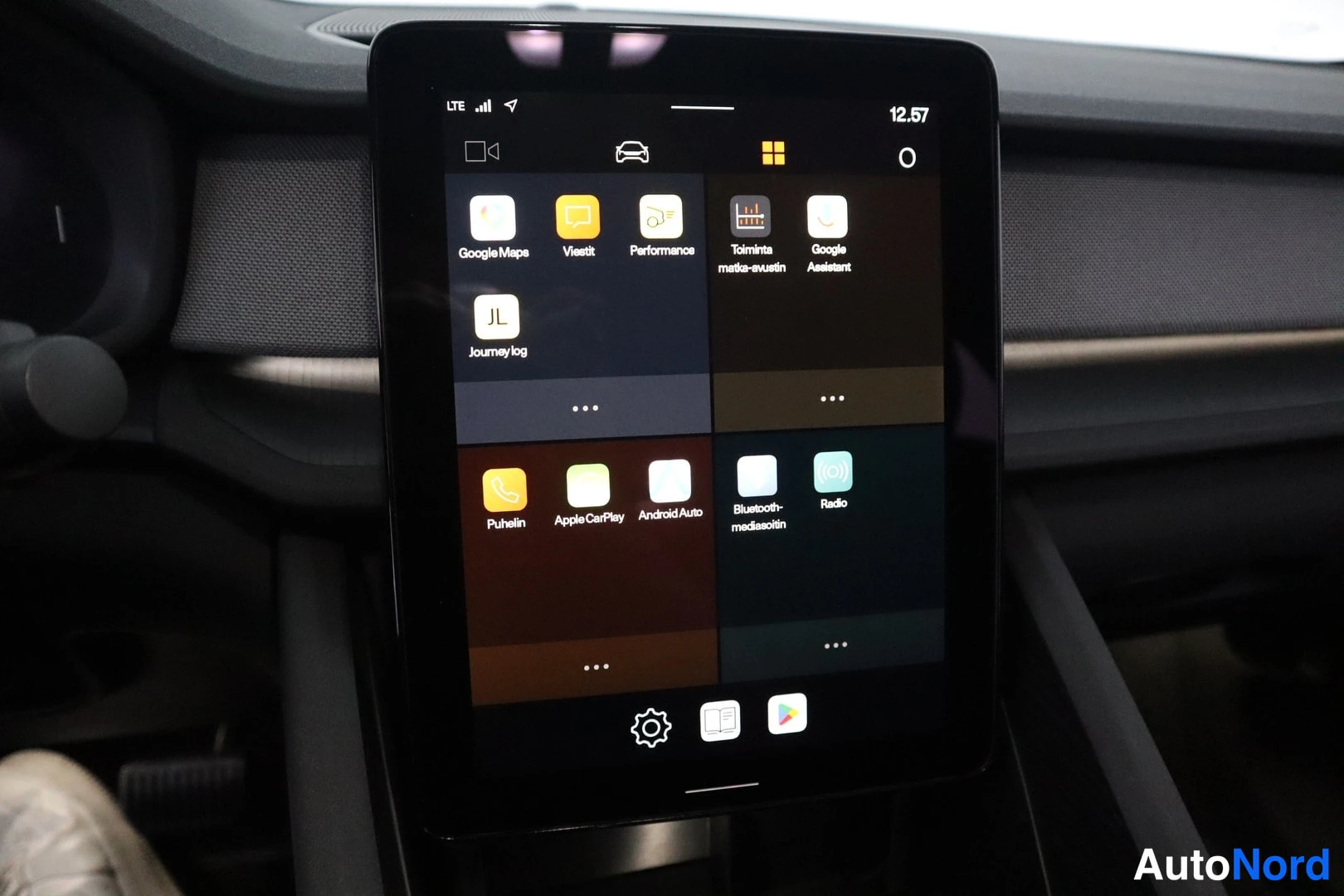 Yksityiskohta: Auton keskinäytön valikko, jossa näkyvät sovellukset kuten Google Maps, Apple CarPlay ja Android Auto.