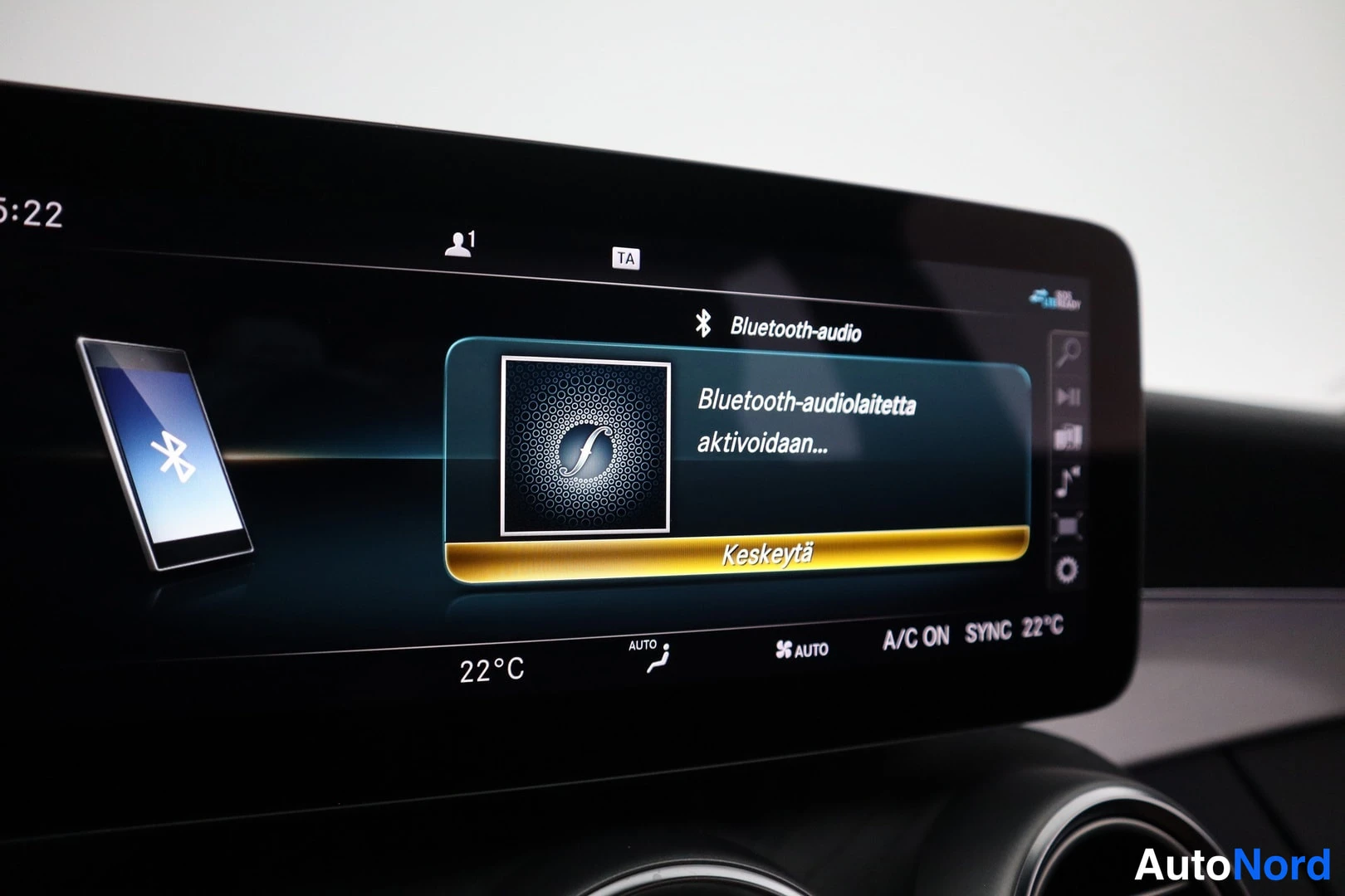 Yksityiskohta: Auton keskikonsolin näyttö, jossa Bluetooth-audiolaitetta aktivoidaan ja näkyy ilmastointiasetukset A/C ON, SYNC 22 °C.