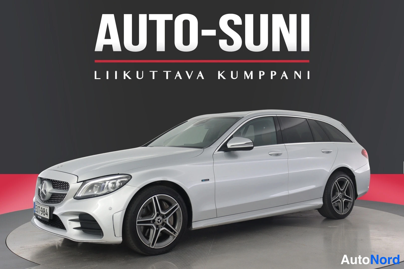 Etuviisto, nokka vasemmalle: Hopeavärinen Mercedes-Benz C-sarjan farmari, etuosta vasemmalle kuvattuna, tummassa studioympäristössä Auto-Suni-kuvituksella.