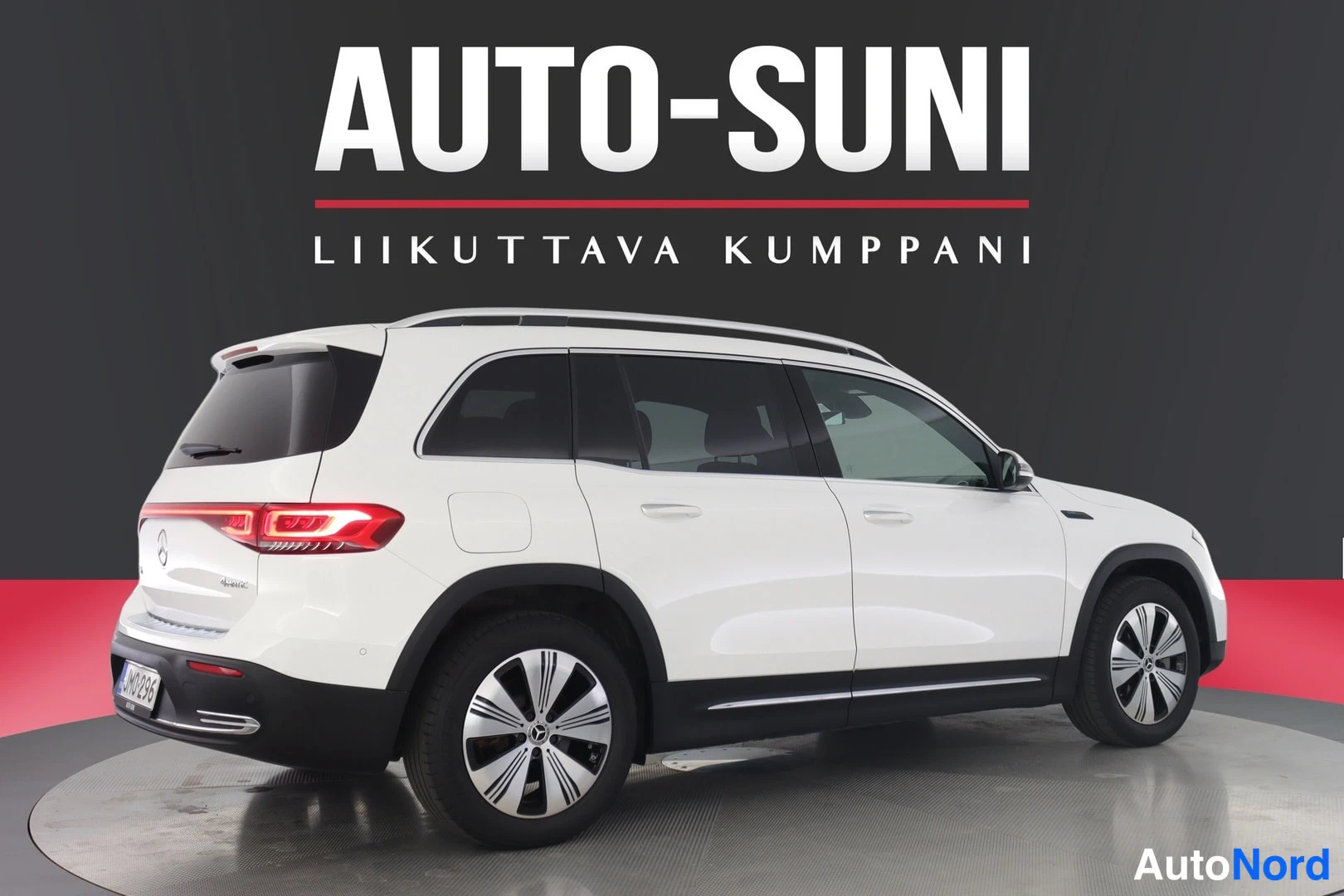 Takaviisto: Valkoinen Mercedes-Benz EQB takaviistoistakulmassa studio-tyyppisessä kuvassa Auto-Suni-taustatekstillä.