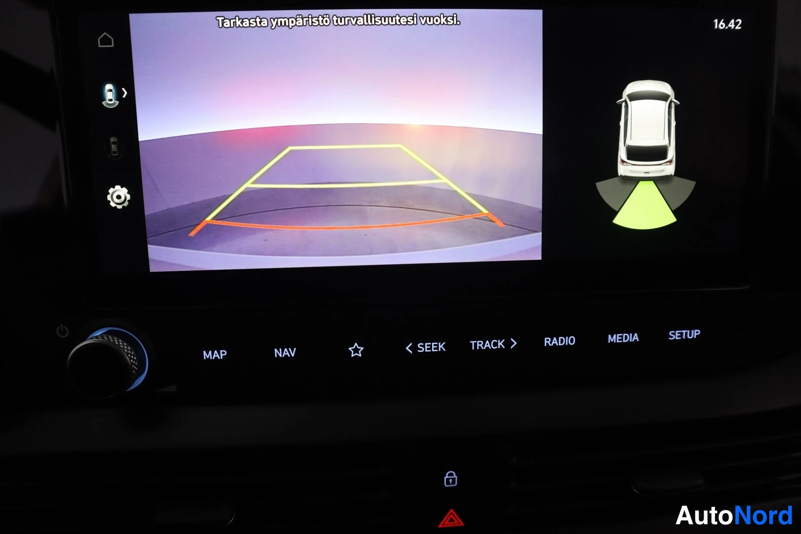 Muu: Infotainment-näyttö, jossa takaosan kamera-näkymä ohjausviivoineen ja tekstillä 'Tarkasta ympäristö turvallisuutesi vuoksi.'; alla MEDIA- ja SETUP-napit.