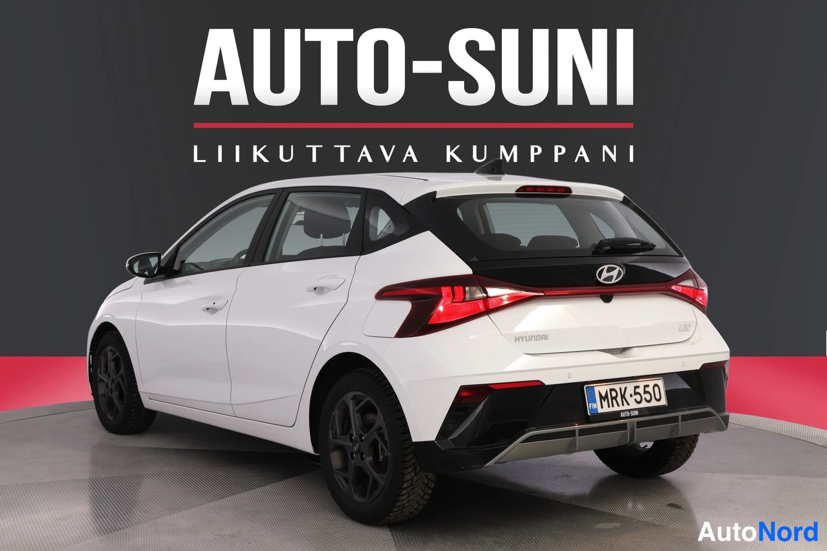 Takaviisto: Valkoinen Hyundai i20 -henkilöauto takaviistosta vasemmalta, HYUNDAI-teksti takaluukussa ja rekisterikilpi.