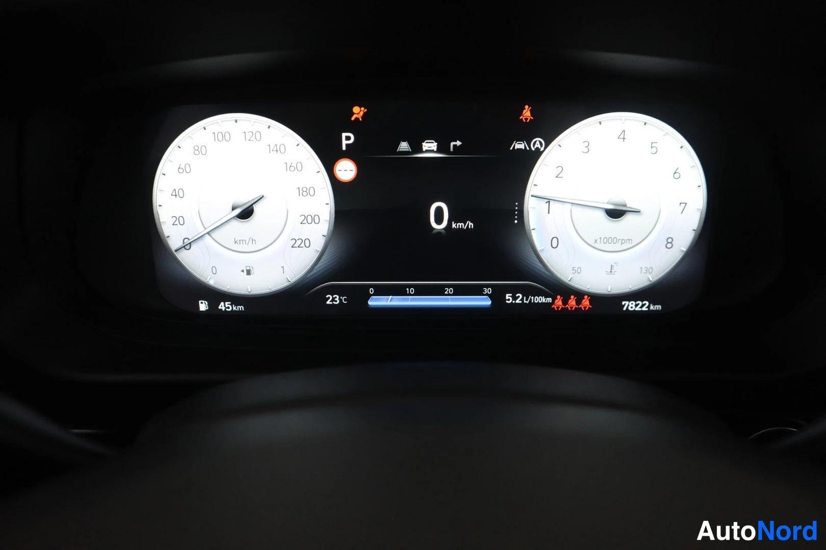 Muu: Kojelaudan mittaristo: nopeusmittari ja kierroslukumittari, näytössä 0 km/h, P-vaihde, 5,2 l/100 km ja 7822 km.