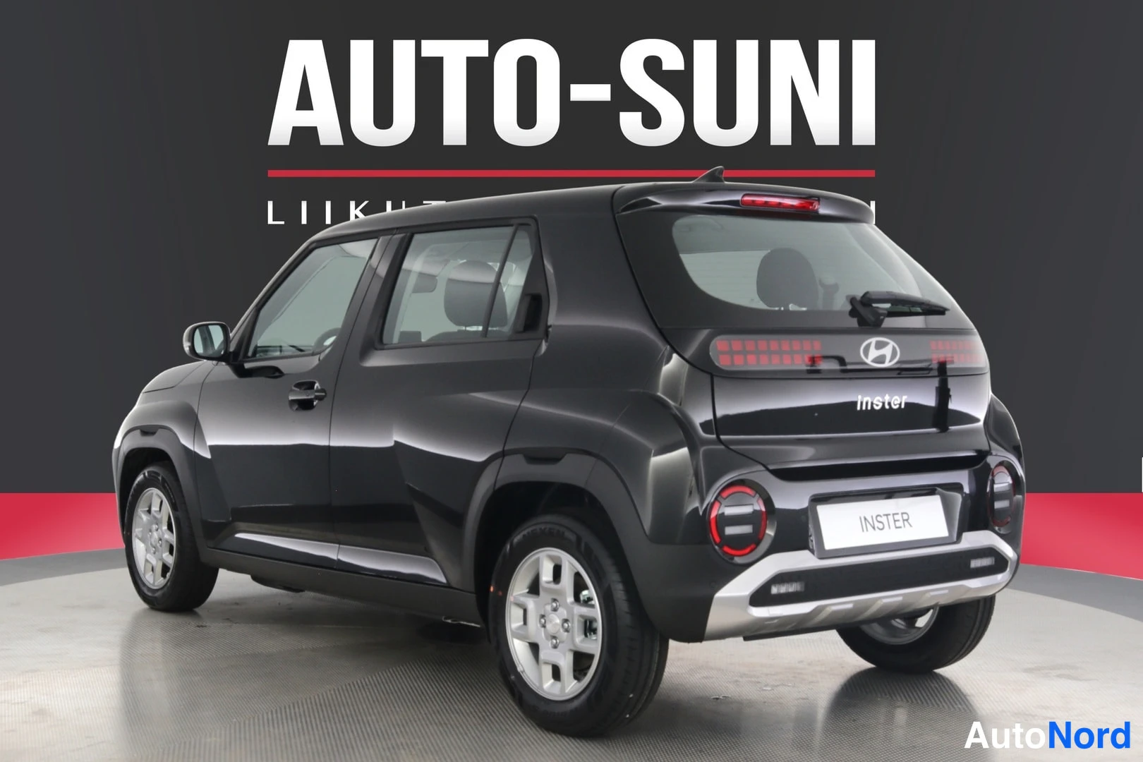 Takaviisto: Musta Hyundai Inster takaviistosta oikealta kuvattuna studiotaustassa.