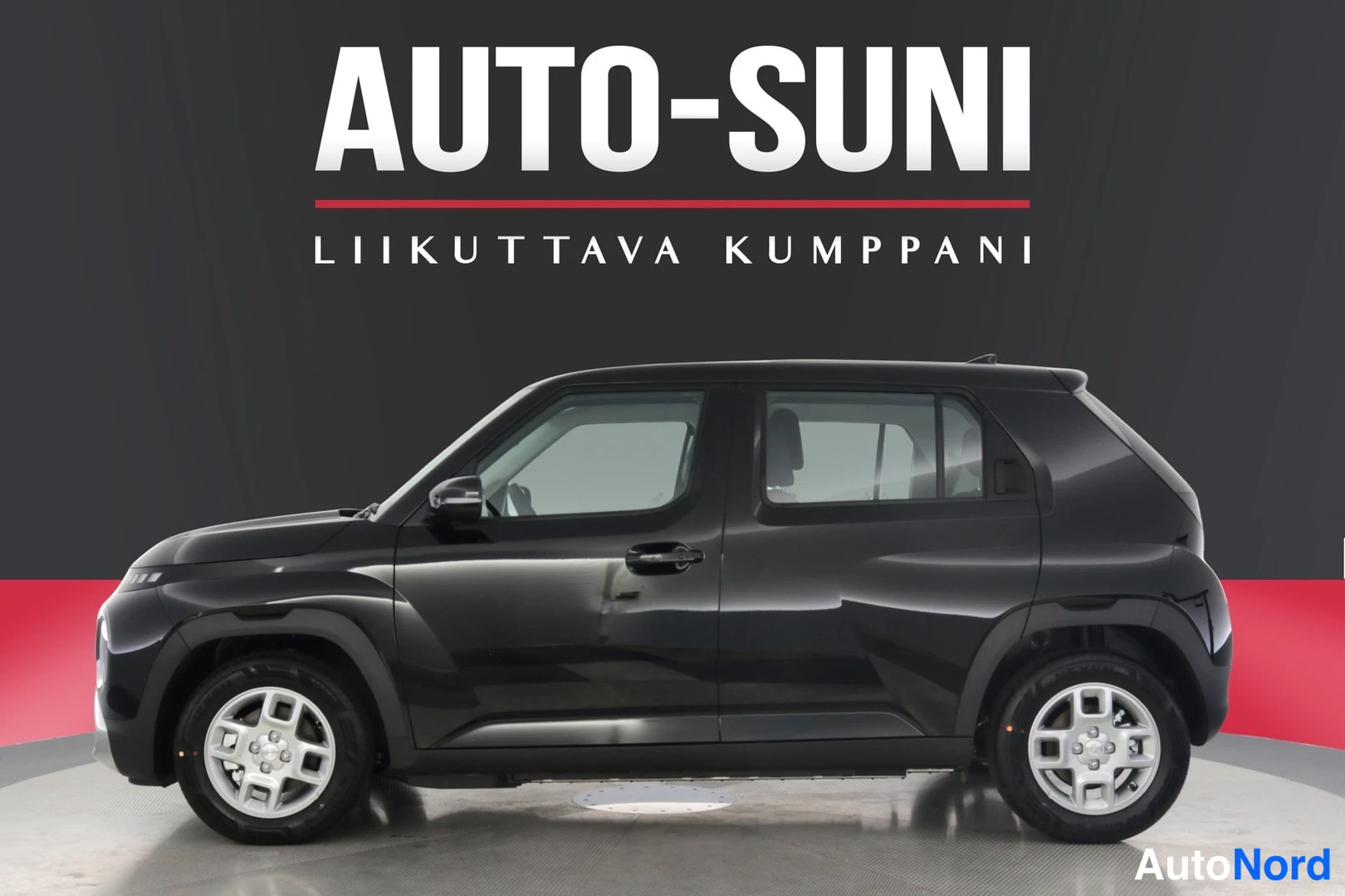 Sivulta: Auton sivuprofiili musta pieni SUV-station wagon studiotäytteessä Auto-Suni-logo taustalla.