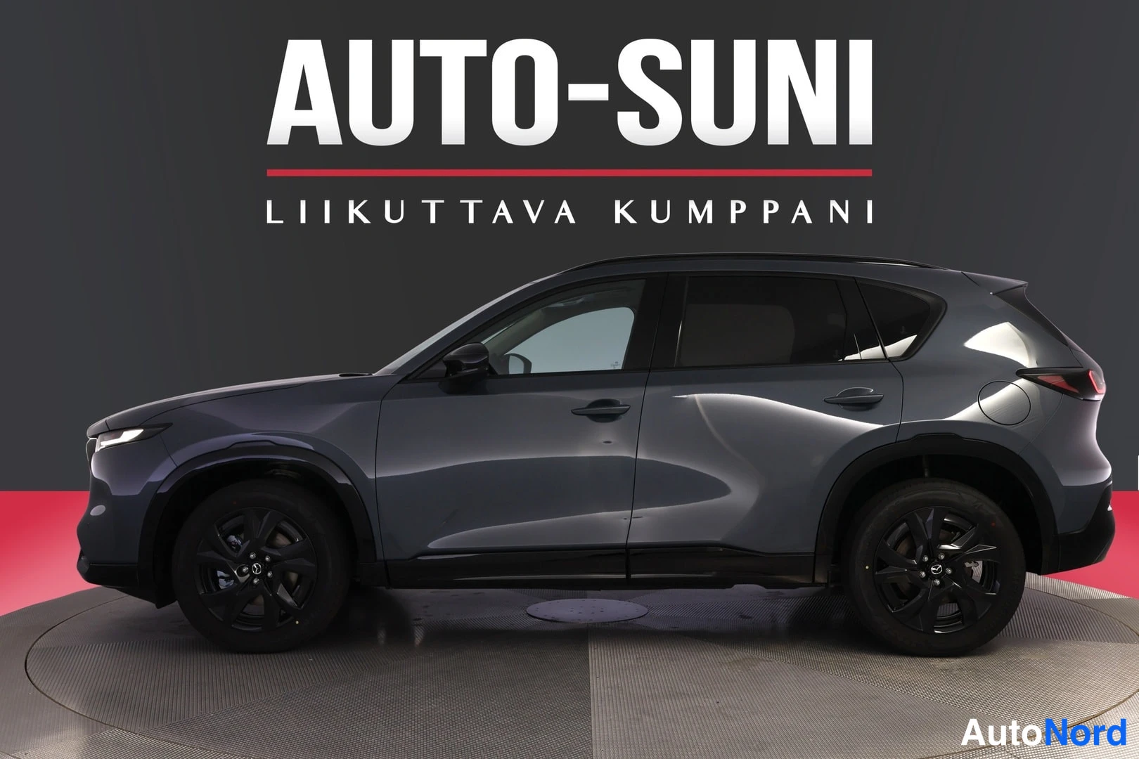Etuviisto, nokka vasemmalle: Auton etukulmasta vasemmalta otettu kuva; tummanharmaa Mazda CX-5 studiovalaistuksessa.