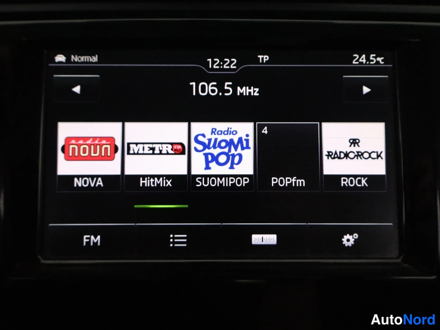 Muu: Kaapelitulkkausnäytön lähikuva: FM 106,5 MHz, asemat NOVA, HitMix, Radio SuomiPop, POPfm ja Radio Rock, näytön alareunassa FM-valikko ja asetukset-ikoni.