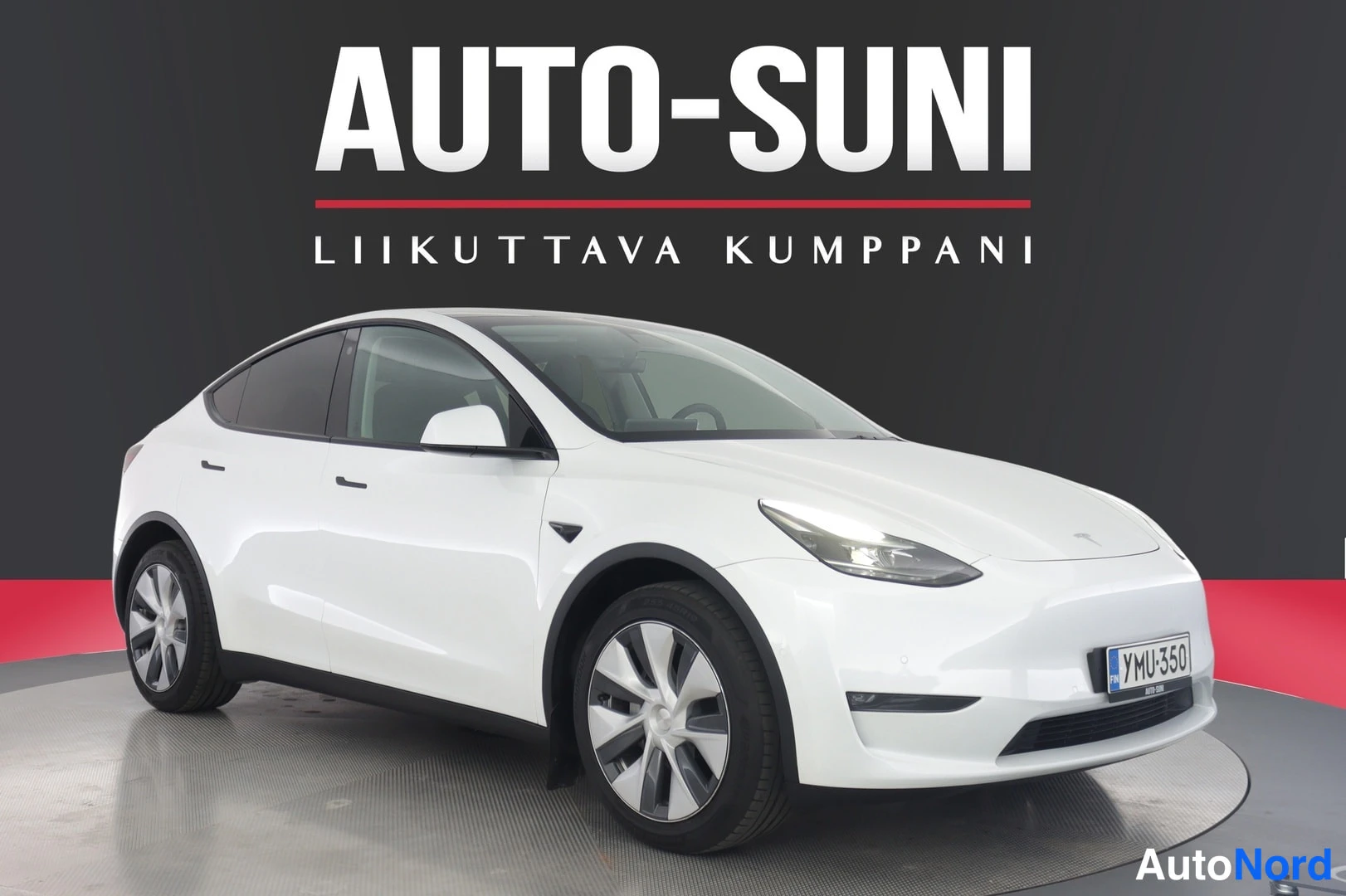 Etuviisto, nokka oikealle: Valkoinen Tesla Model Y etuviistosta oikealta kuvattuna, rekisterikilpi; kahdensävyiset kevytmetallivanteet.