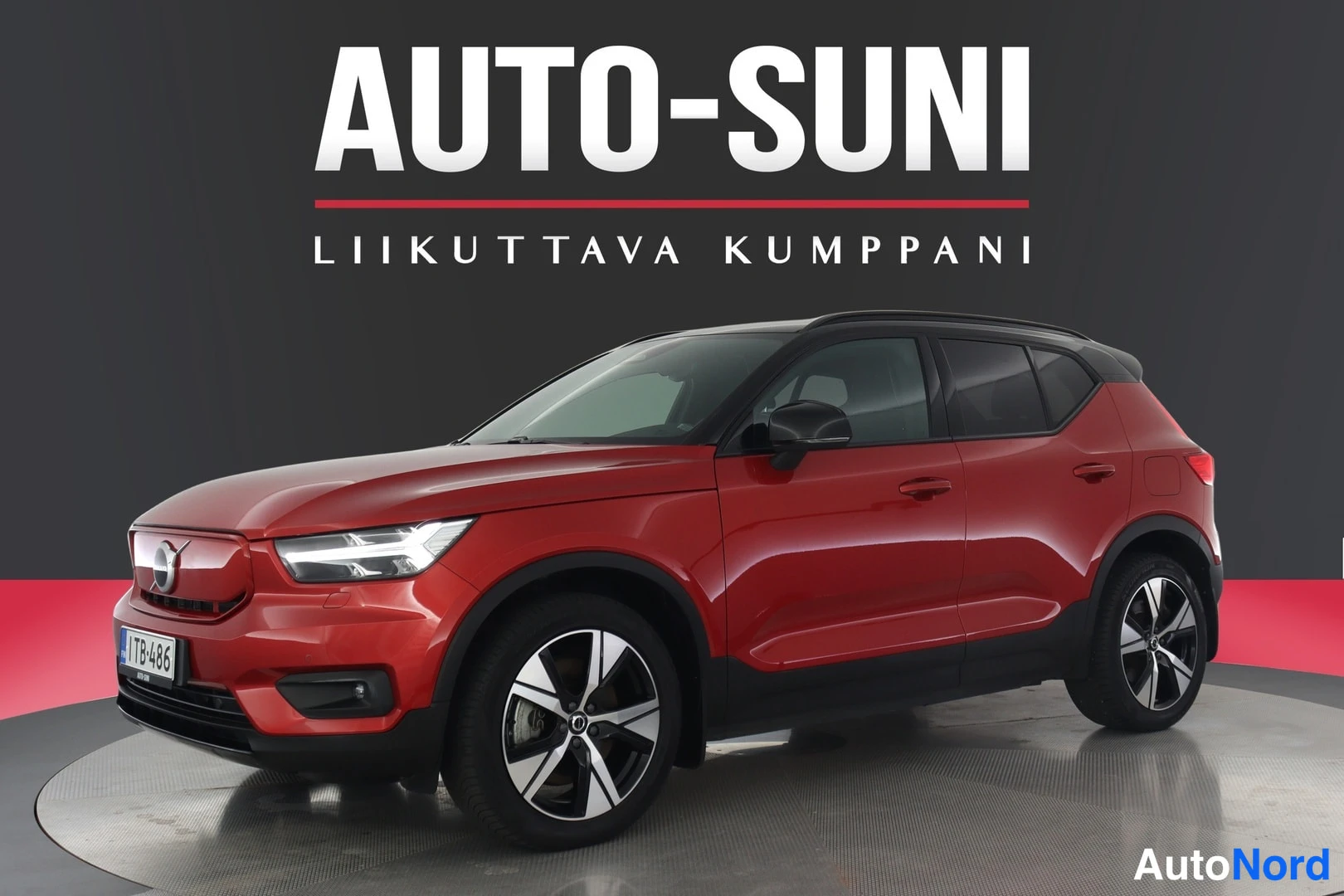Etuviisto, nokka vasemmalle: Punainen Volvo XC40 -mallinen auto etukulmasta valokuvattuna studiossävyisellä taustalla.