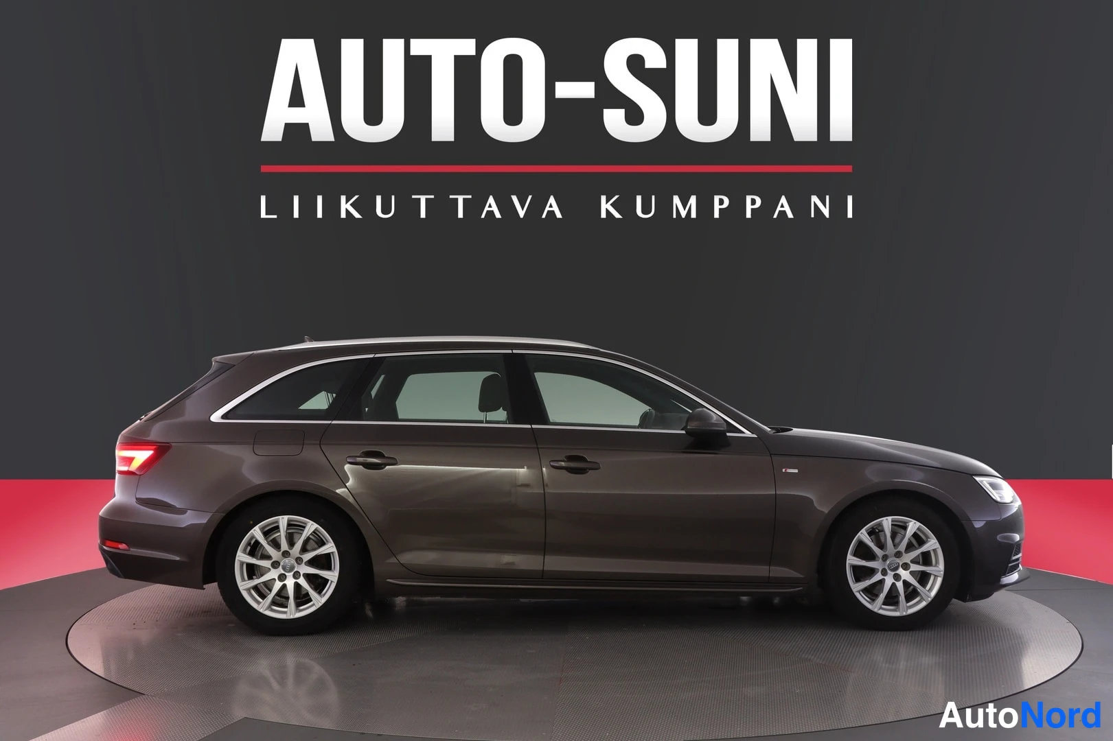 Takaviisto: Auton oikea kylki ja takaosa hallintatilassa, taustalla mainoskyltti.