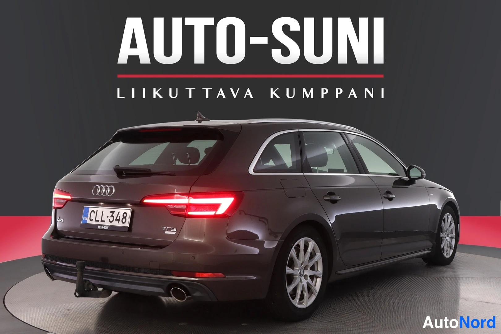 Takaviisto: Auton takaosa ja oikea kylki, rekisterikilpi, taustalla mainoskyltti.