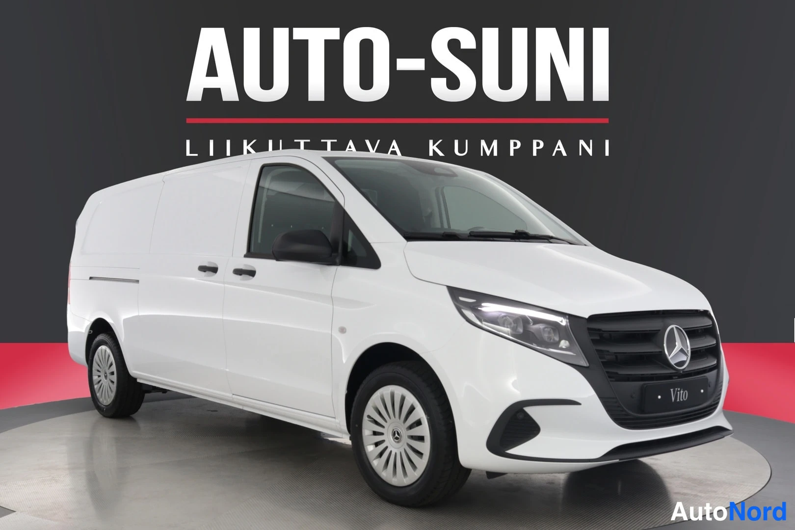 Etuviisto, nokka oikealle: Mercedes-Benz Vito -pakettiauto etuviistossa oikealta, valokuvio valoina ja pimeinä keskusautosalin taustaa vasten