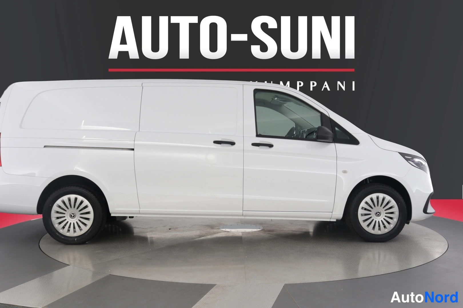 Sivulta: Mercedes-Benz Vito -pakettiauto suoraan sivulta vasemmalta, valokuvio valoina ja pimeinä keskusautosalin taustaa vasten