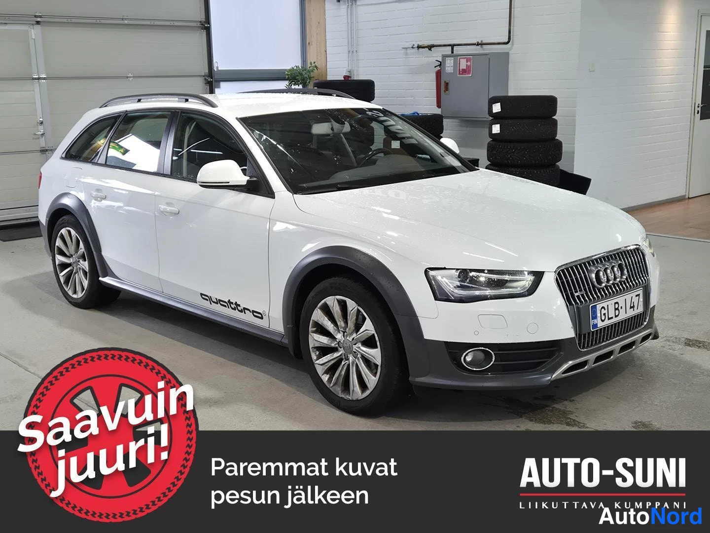 Etuviisto, nokka oikealle: Valkoinen farmariauto autonäyttelytilassa, etukulmasta oikealta kuvattuna, rekisterikilpi.