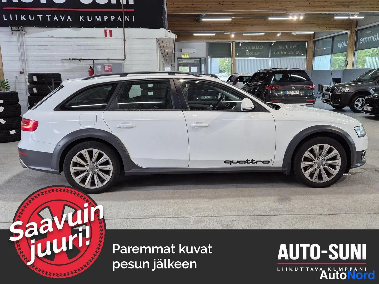 Sivulta: Valkoisen farmariautin sivuprofiili autosalonissa, mustat lokasuojakkeet ja quattro-tekstidekali oviin.