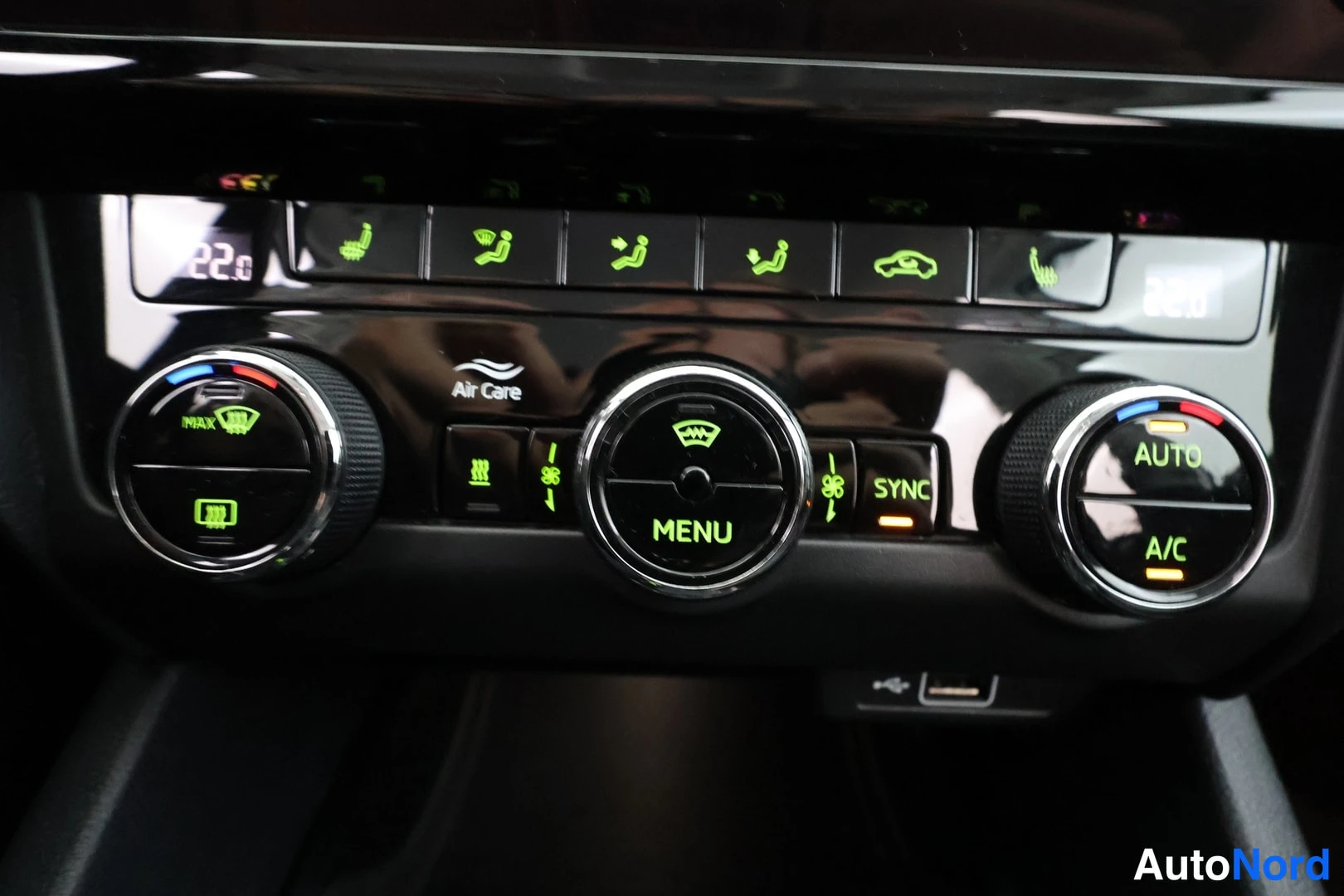 Muu: Ilmastointipaneeli vihreillä näytöillä 22.0 ja 18.0, tekstit Air Care, MENU, SYNC, AUTO ja A/C sekä lämmitettävien istuinten painikkeet.