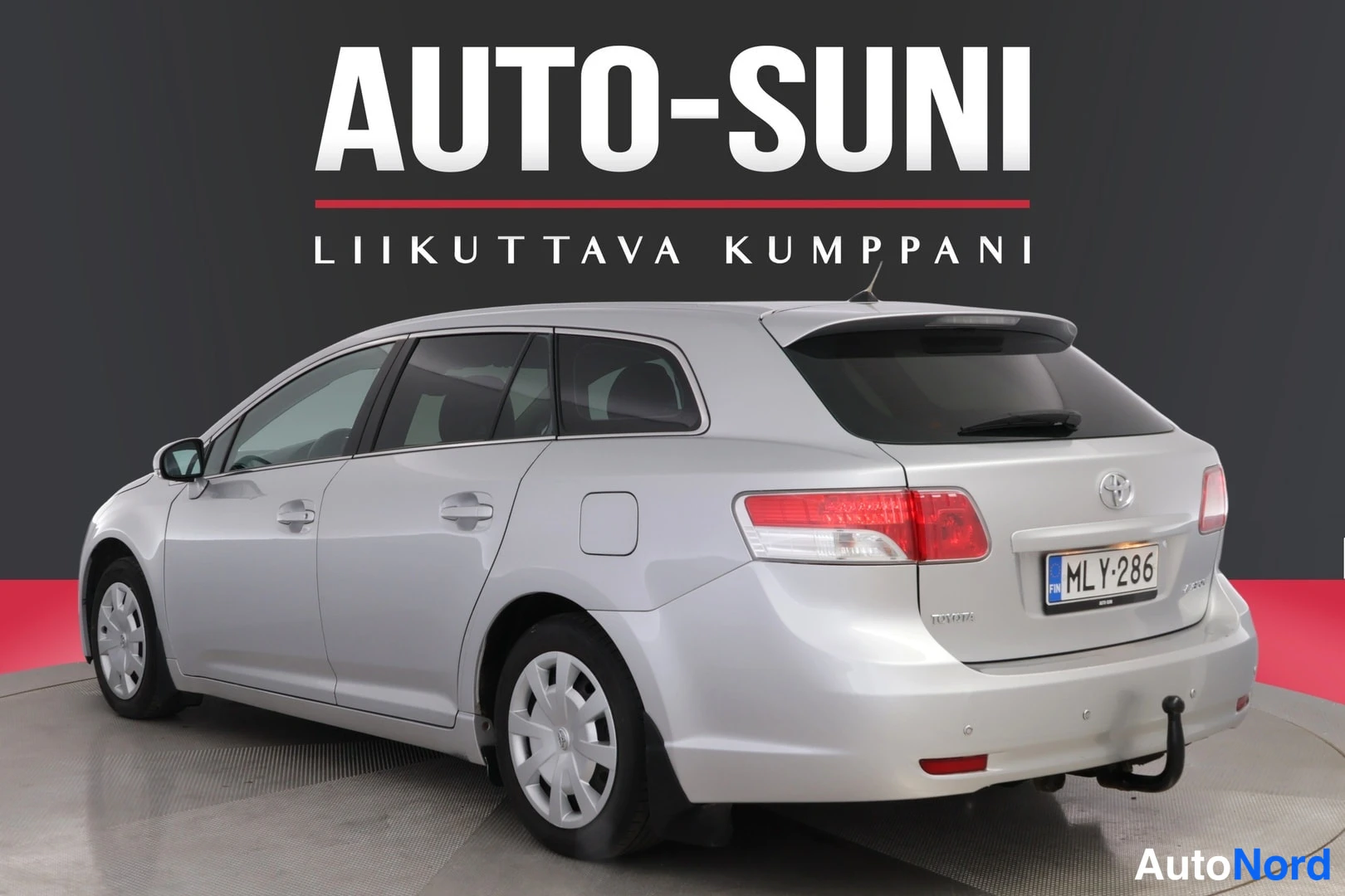 Takaviisto: Hopeanvärinen farmariauto takaviistosta kuvattuna toiselta puolelta, takavalot ja rekisteritunnus näkyvät, perävetokoukku.