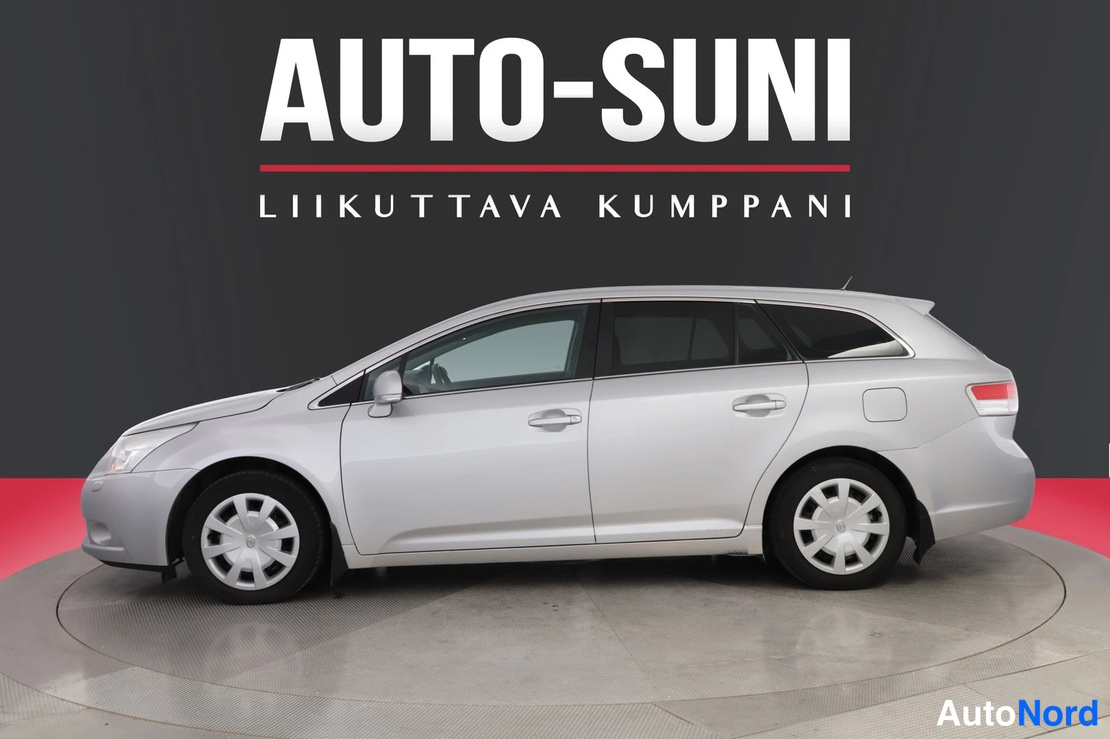 Sivulta: Hopeanharmaa Toyota Avensis -farmari kuvattuna sivulta studiotaustaa vasten.