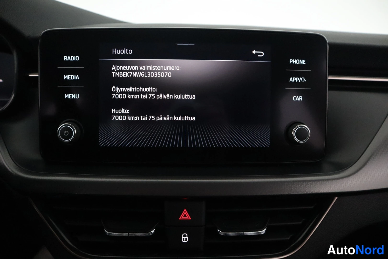 Yksityiskohta: Infotainment-näytön huoltosivu, jossa ajoneuvon valmistenumero ja huoltoaikatiedot.