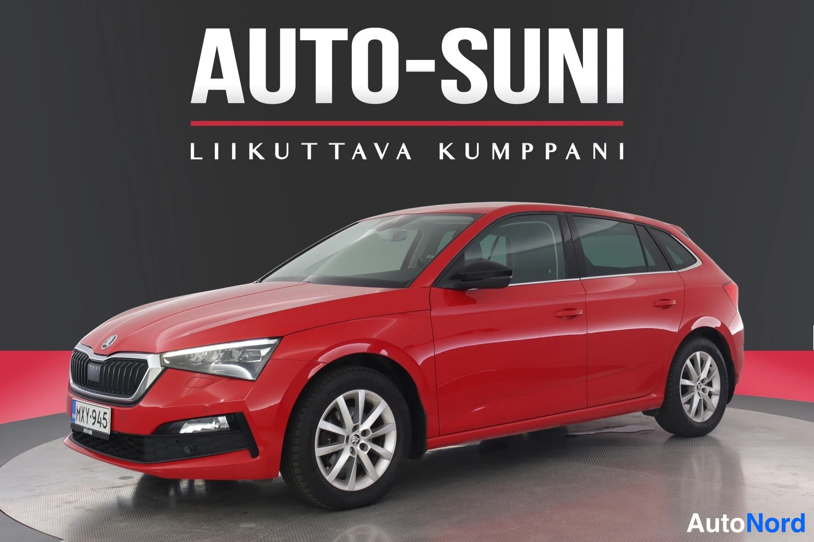 Etuviisto, nokka vasemmalle: Punaisen Skoda Scalan etukulmanakymä studio-asetelmassa; LED-ajovalot ja kevytmetallivanteet näkyvissä.