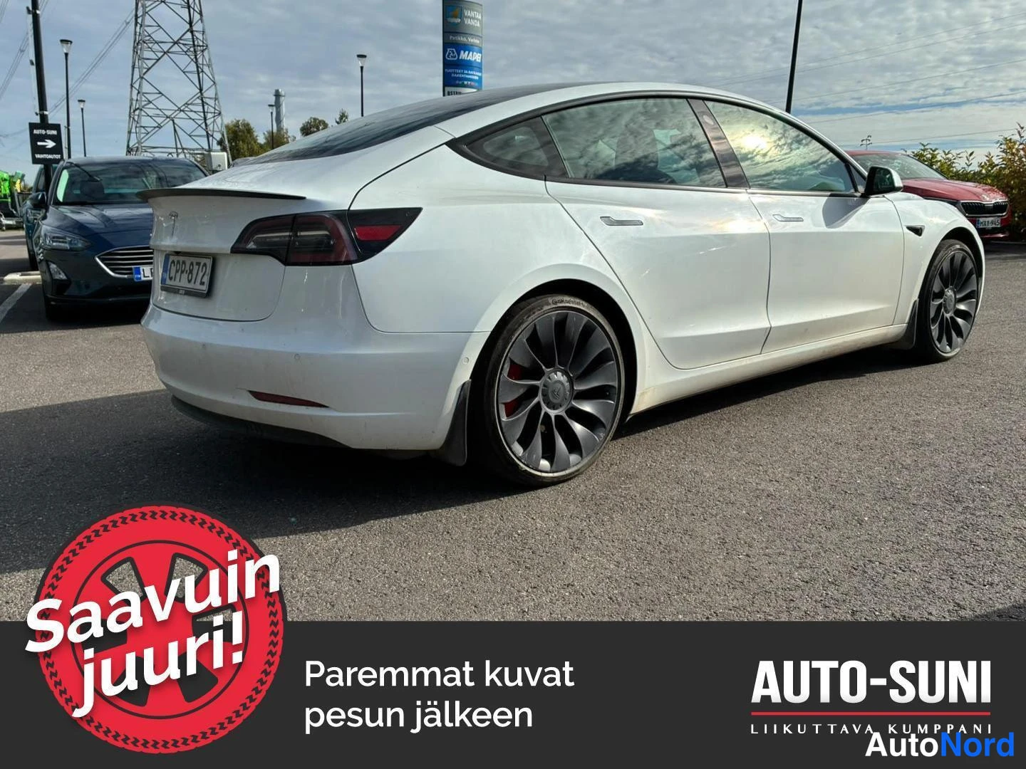 Takaviisto: Valkoinen sedan takaosan ja oikean kyljen kolmesta neljäsosasta, tummat kevytmetallivanteet ja punaiset jarrusatulat näkyvissä.