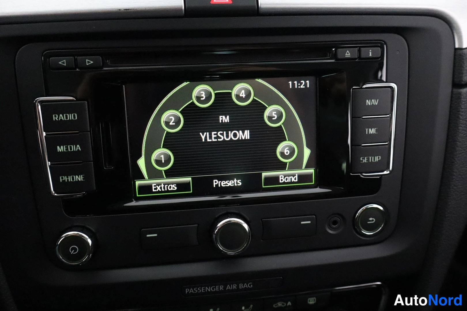 Muu: Kojelaudan radiopaneeli: navigointipainike (NAV), TMC ja SETUP, näytöllä YLEisradio FM-asema, kello 11:21.