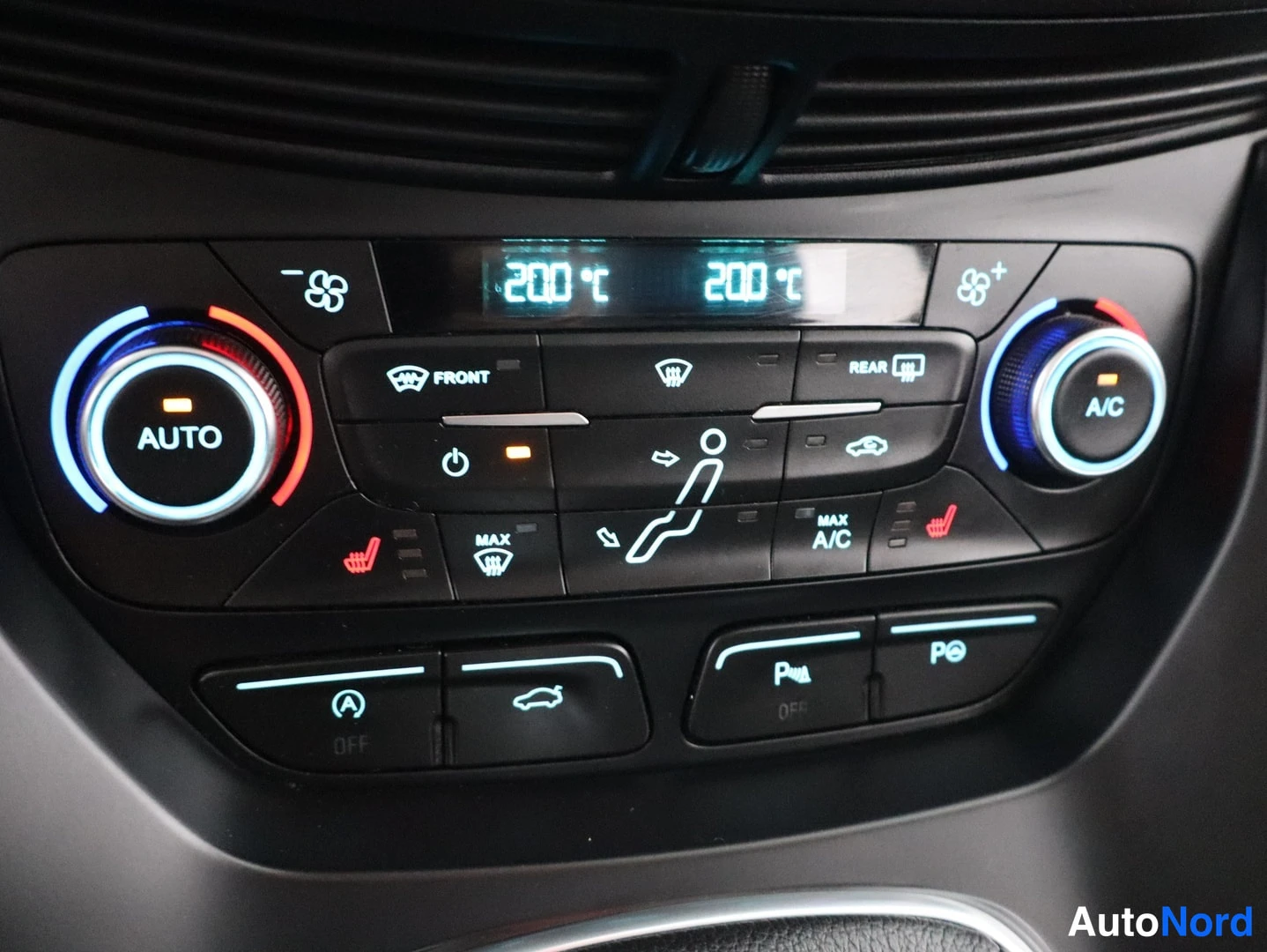 Yksityiskohta: Ilmastointipaneeli, jossa AUTO- ja A/C-napit, molempien puolten lämpötilat 20,0 °C, lämmitettävien istuinten painikkeet sekä peilien ja pysäköintijärjestelmän p