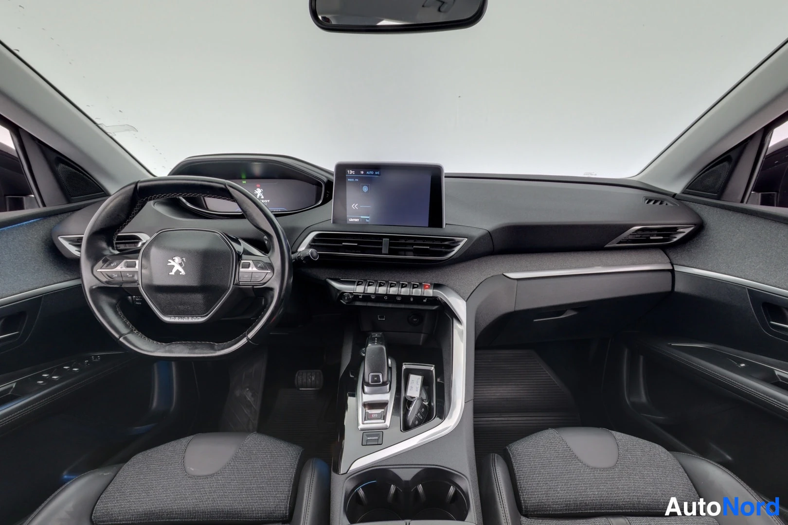 Muu: Peugeot 3008:n ohjaamo kohtisuoraan edestä: pieni multimedianäyttö keskellä, i-Cockpit-näyttö ja tinktyöpyörä Peugeot-leijonalla, automaattivaihteiston valitsin