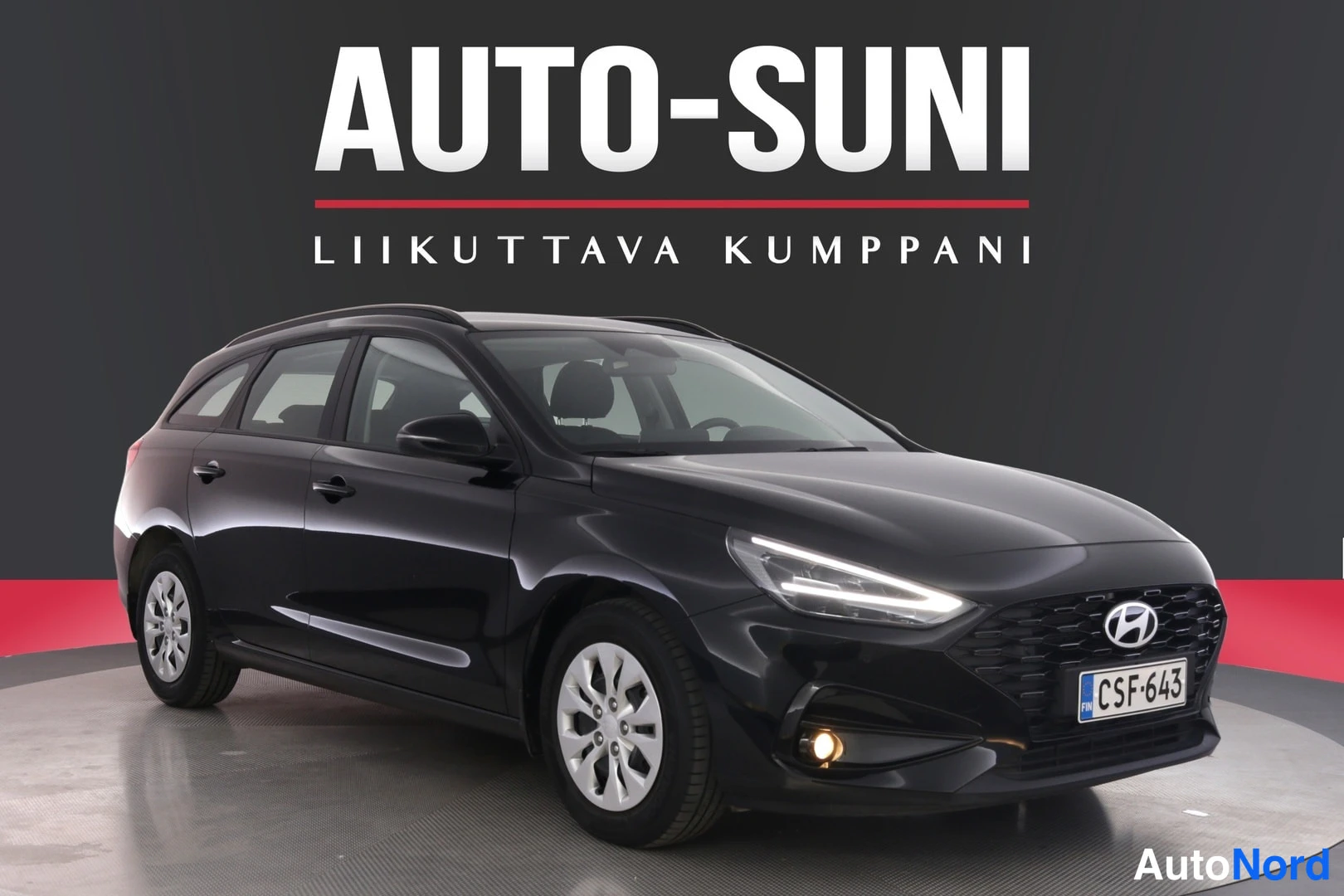 Etuviisto, nokka oikealle: Musta Hyundai i30 -farmari kolmivartalokulmassa edestä oikealta, etusäleikkö ja ajovalot näkyvissä, rekisterikilpi.