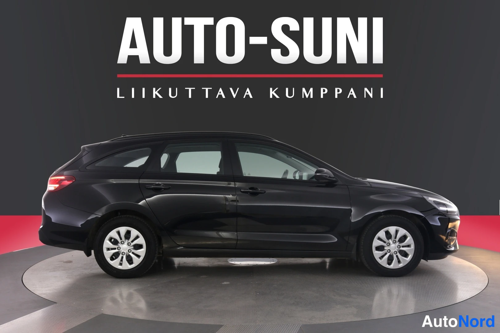 Sivulta: Mustan Hyundai i30 -farmarin sivukuva vasemmalta, neljä ovea ja kattotelineet näkyvissä.