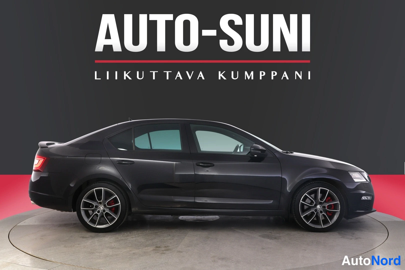 Sivulta: Sivukuvassa musta sedan-henkilöauto, punaiset jarrusatulat ja kevytmetallivanteet näkyvissä.