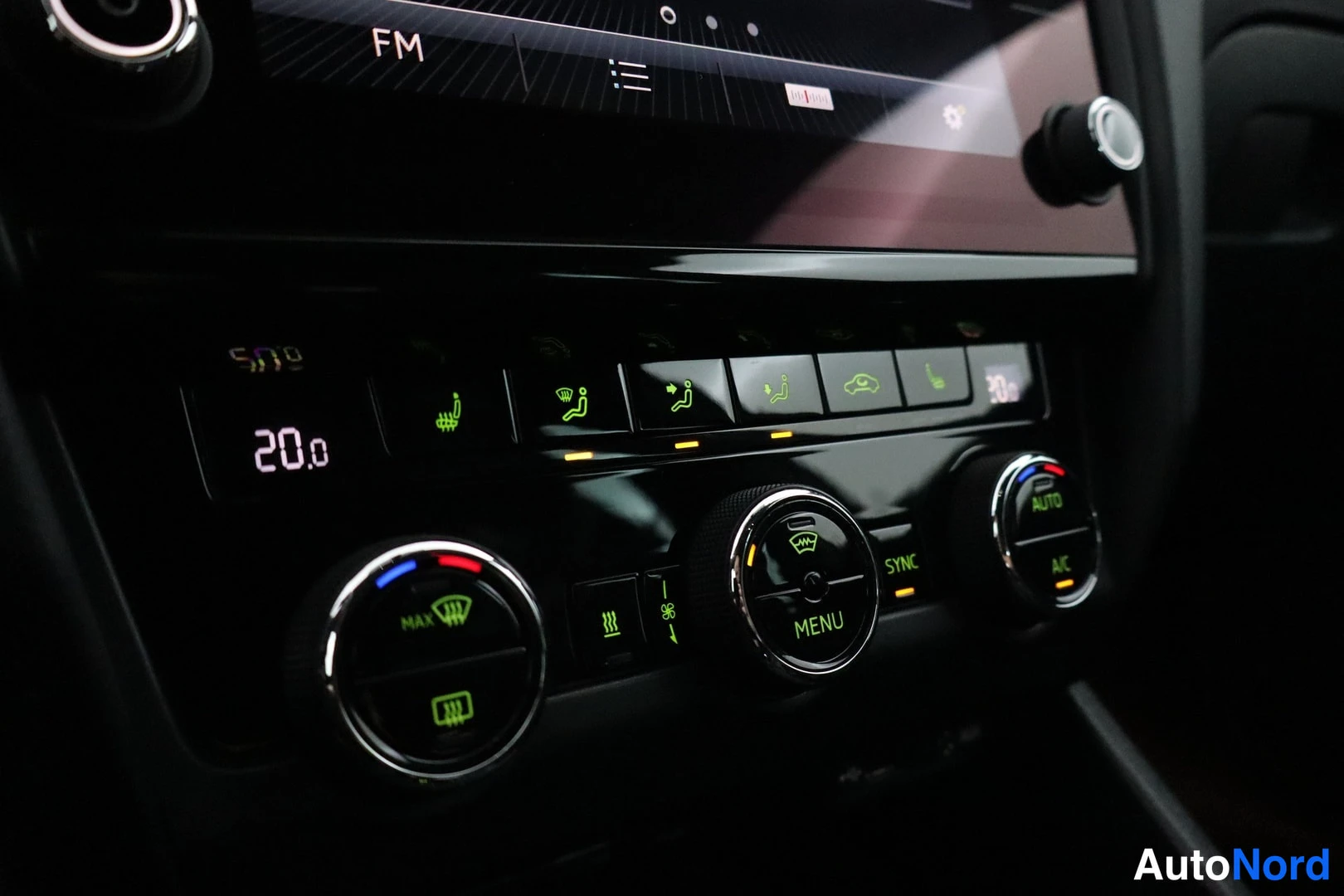 Muu: Ilmastointipaneeli pyöreillä nuppeilla, näytöllä 20.0, painikkeet MAX, SYNC, AUTO, A/C ja MENU näkyvillä.