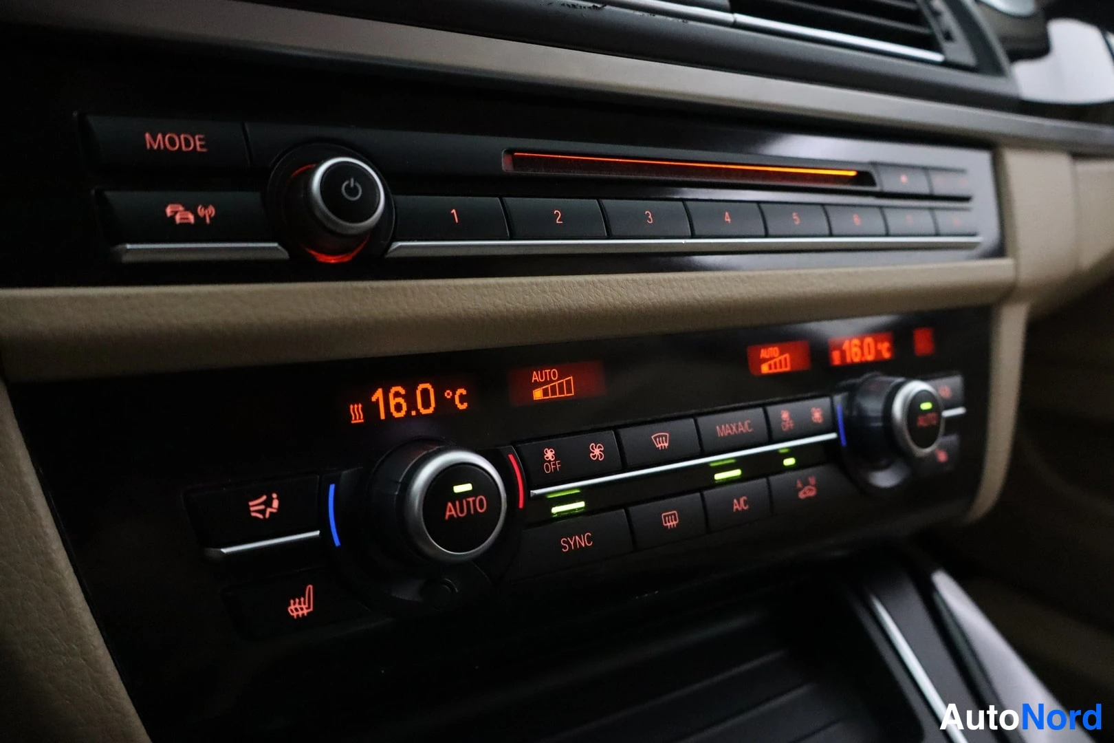 Muu: Autoon sisätila: keskikonsolin radionäyttö ja kaksialueilmastointi, näytössä 16,0 °C, AUTO- ja SYNC-painikkeet näkyvät.