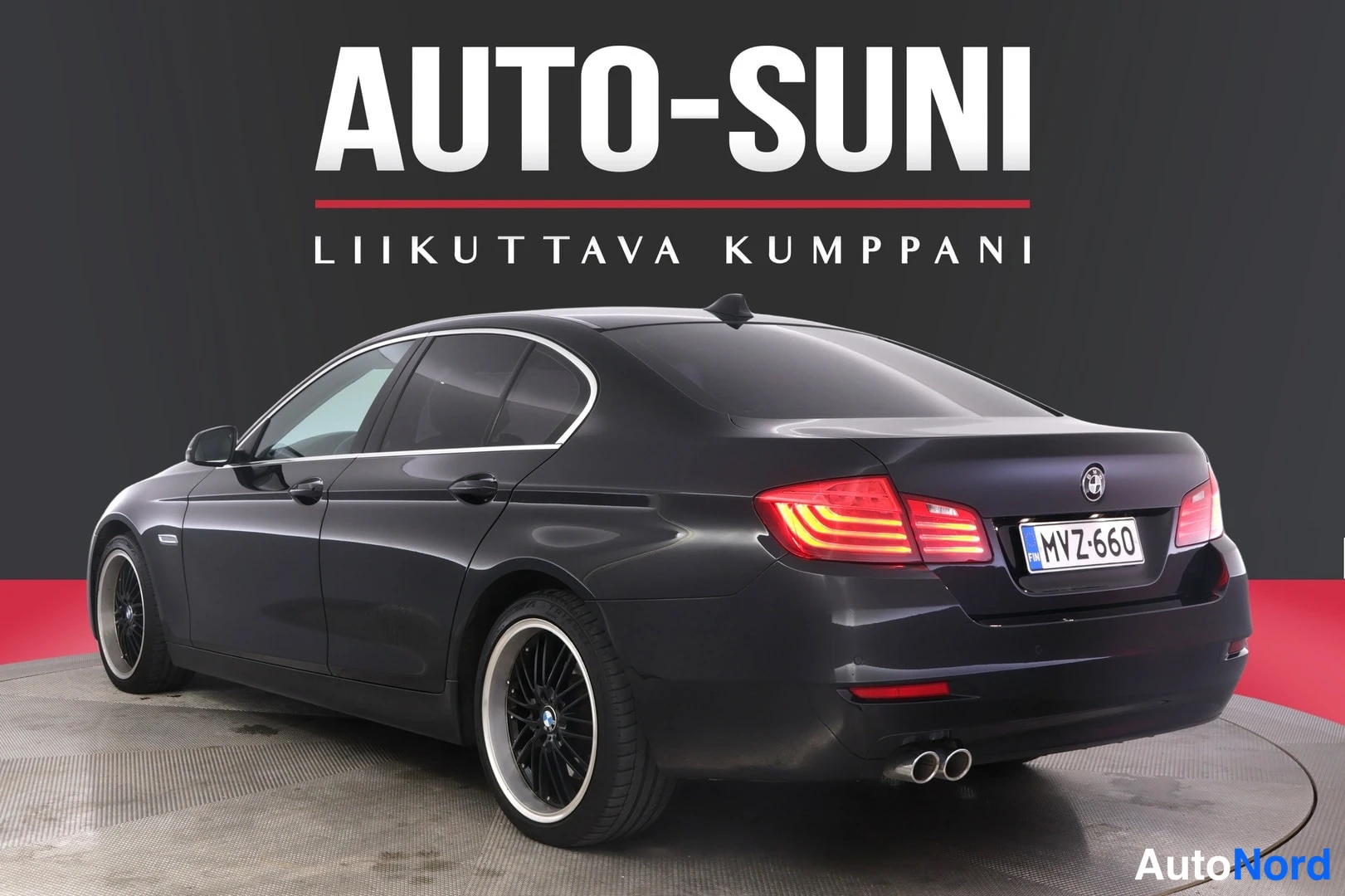 Takaviisto: Mustan sedanin takaosa oikealta, rekisterikilpi, kaksoispakoputket, neliväräinen musta alumiinivanne, sivupeili ja kromireunus.