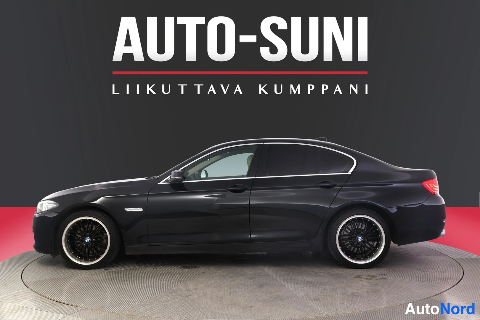 Sivulta: BMW:n sedanin sivukuva: musta koripaneeli, kevytmetallivanteet ja paneliautotallin tausta