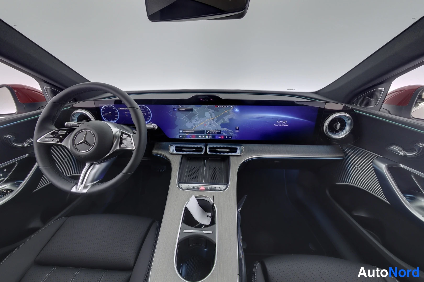 Muu: Auton ohjaamo edestä: Mercedes-musteri, laaja digitaalinäyttö karttanäkymällä ja mustat penkit.
