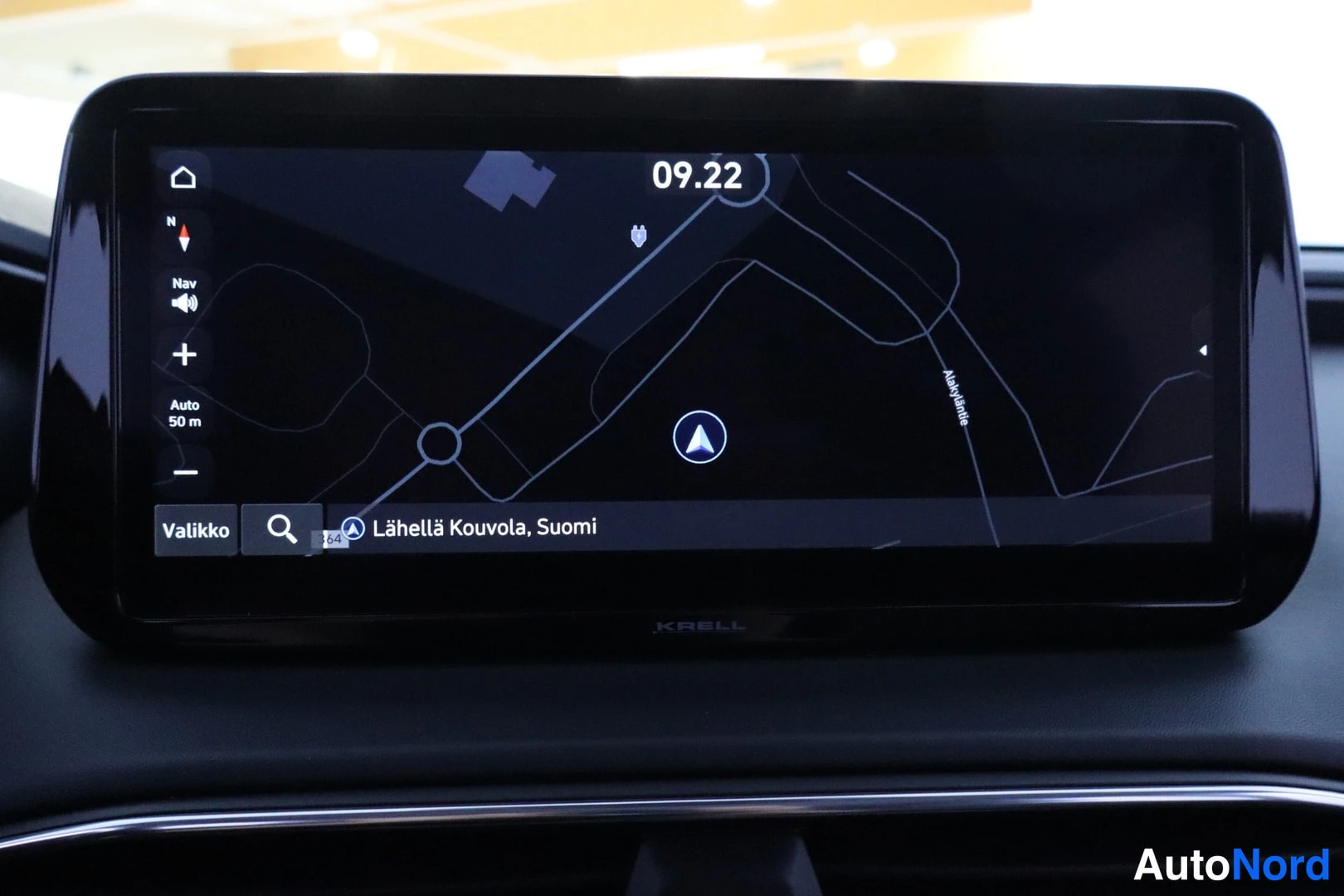 Yksityiskohta: Auton infotainment-näytöllä on auki reittinäkymä kartalla, tekstillä 'Lähellä Kouvola, Suomi'. Näytön alareunassa lukee KRELL.