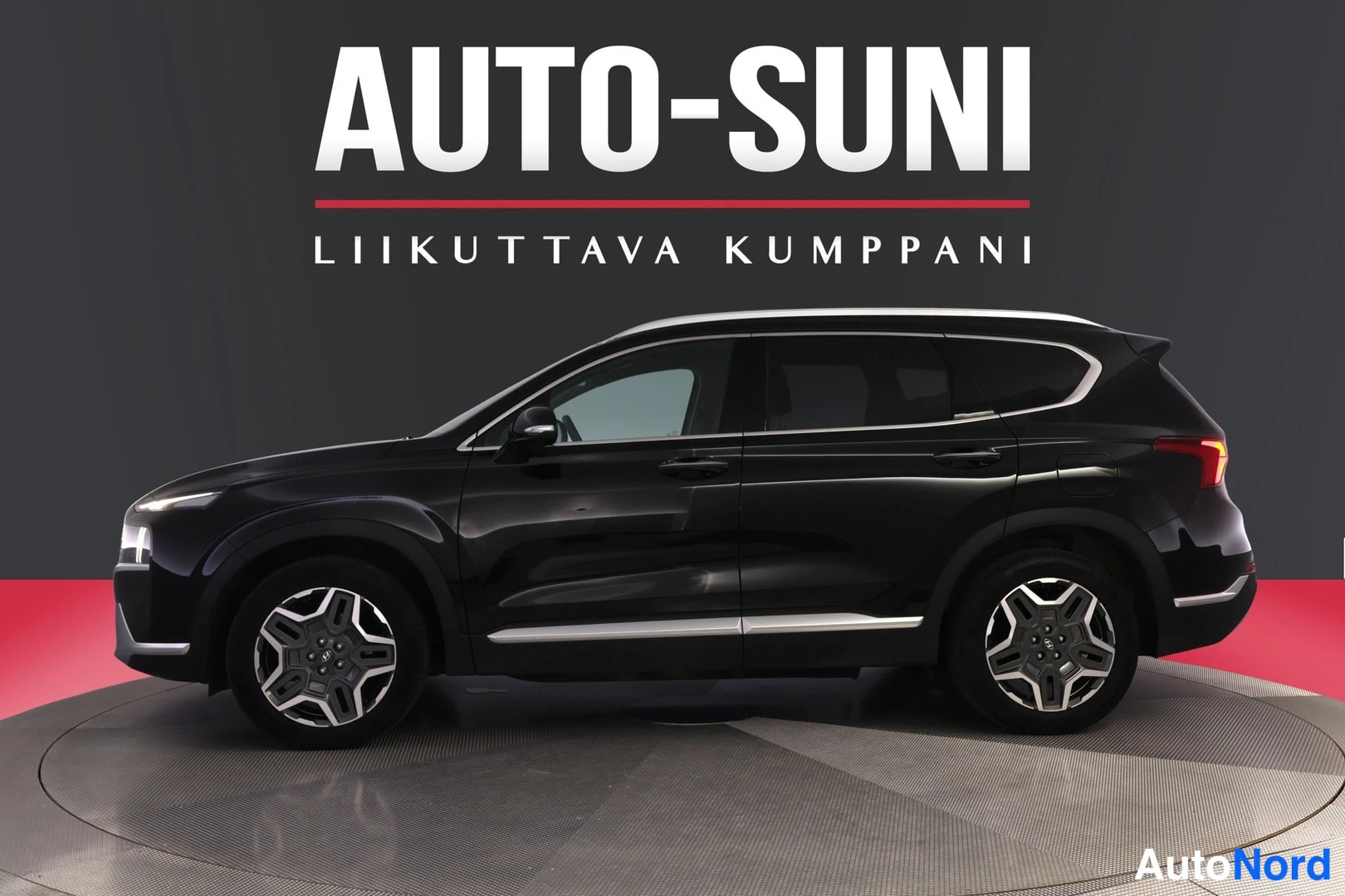 Takaviisto: Musta Hyundai Santa Fe -tyylinen katumaasturu sivulta takaa kuvattuna studiotaustaa vasten, kromilistat ovissa ja alapaanessa.