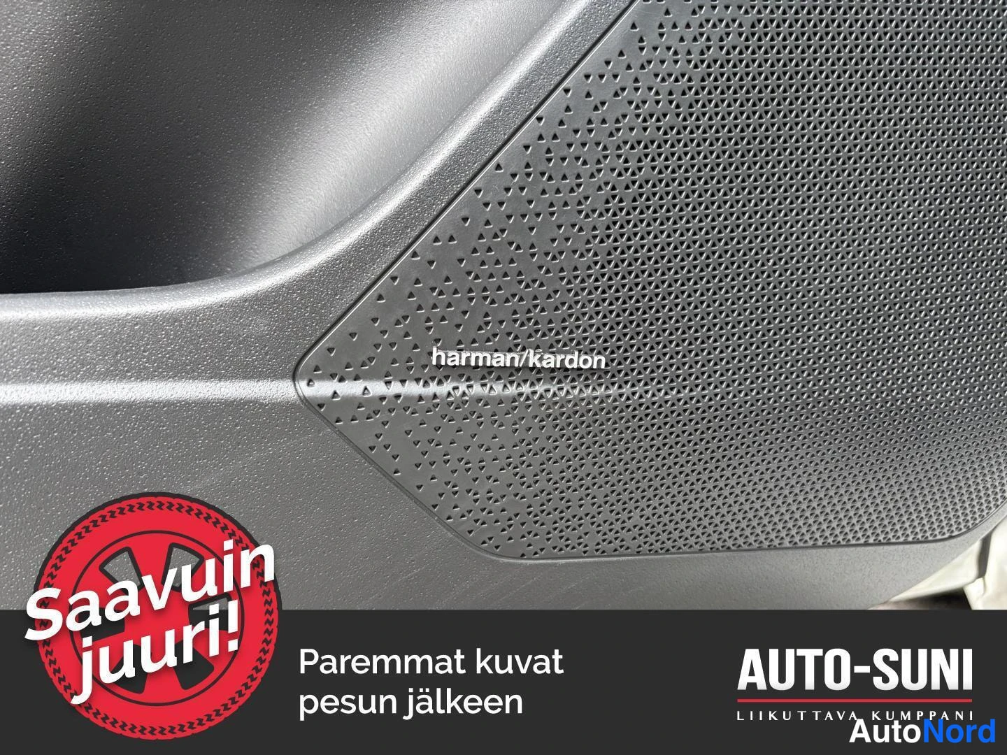 Edestä: Lähikyva harman/kardon-merkinnöllä varustetusta kaiuttimesta oven sisäpaneelissa; kalvo ja hopeanvärinen paneli. Kuvassa markkinointitekstit 'Saavuin juuri!' ja