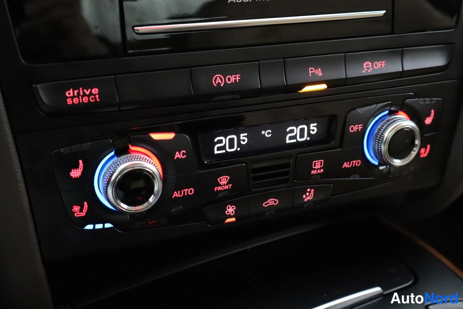 Muu: Audiin keskikonsolin ilmastointipaneeli: kaksi pyöreää säätöritilää, näyttö 20.5 °C molemmilta puolilta, AC-, AUTO- ja OFF-napit, punainen taustavalo, yläpuolel