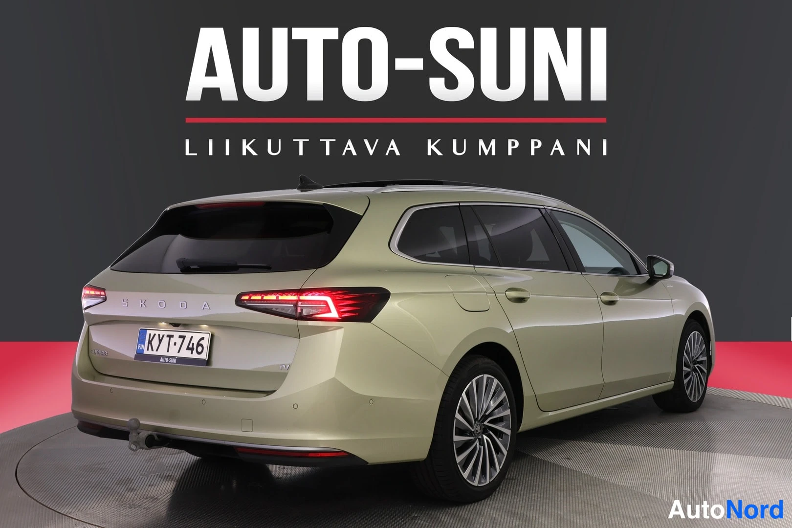 Takaviisto: Skoda Superb Combi farmarin takakulma, perävalot ja rekisteritunnus näkyvät, AUTO-SUNI-tunnus taustalla.