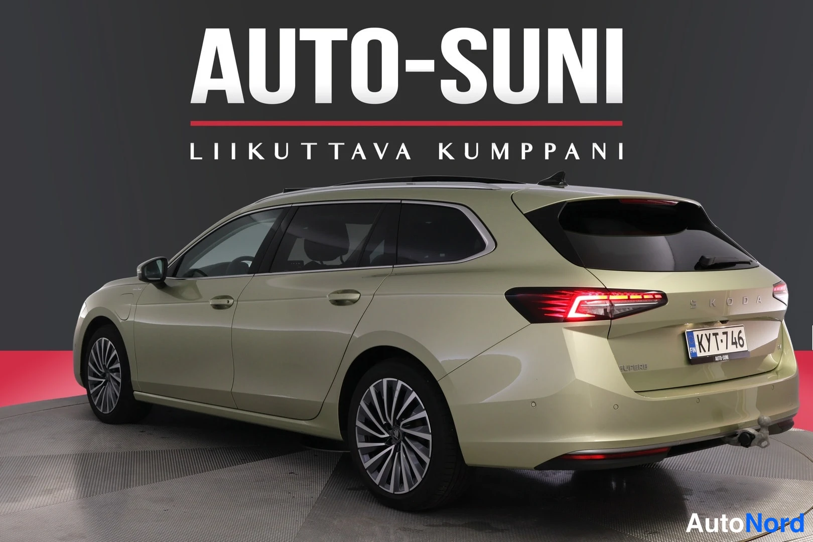 Takaviisto: Skoda Superb Combi farmarin toinen takakulma, perävalot ja vetokoulu näkyvät, rekisteritunnus, AUTO-SUNI-tunnus taustalla.