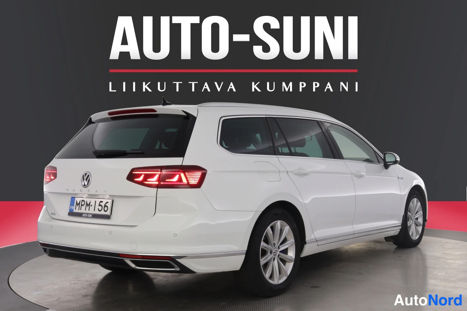 Takaviisto: Valkoinen farmariauto kuvattu takaa sivusuunnassa, rekisterikilpi, myyjän logo Auto-Suni taustalla.