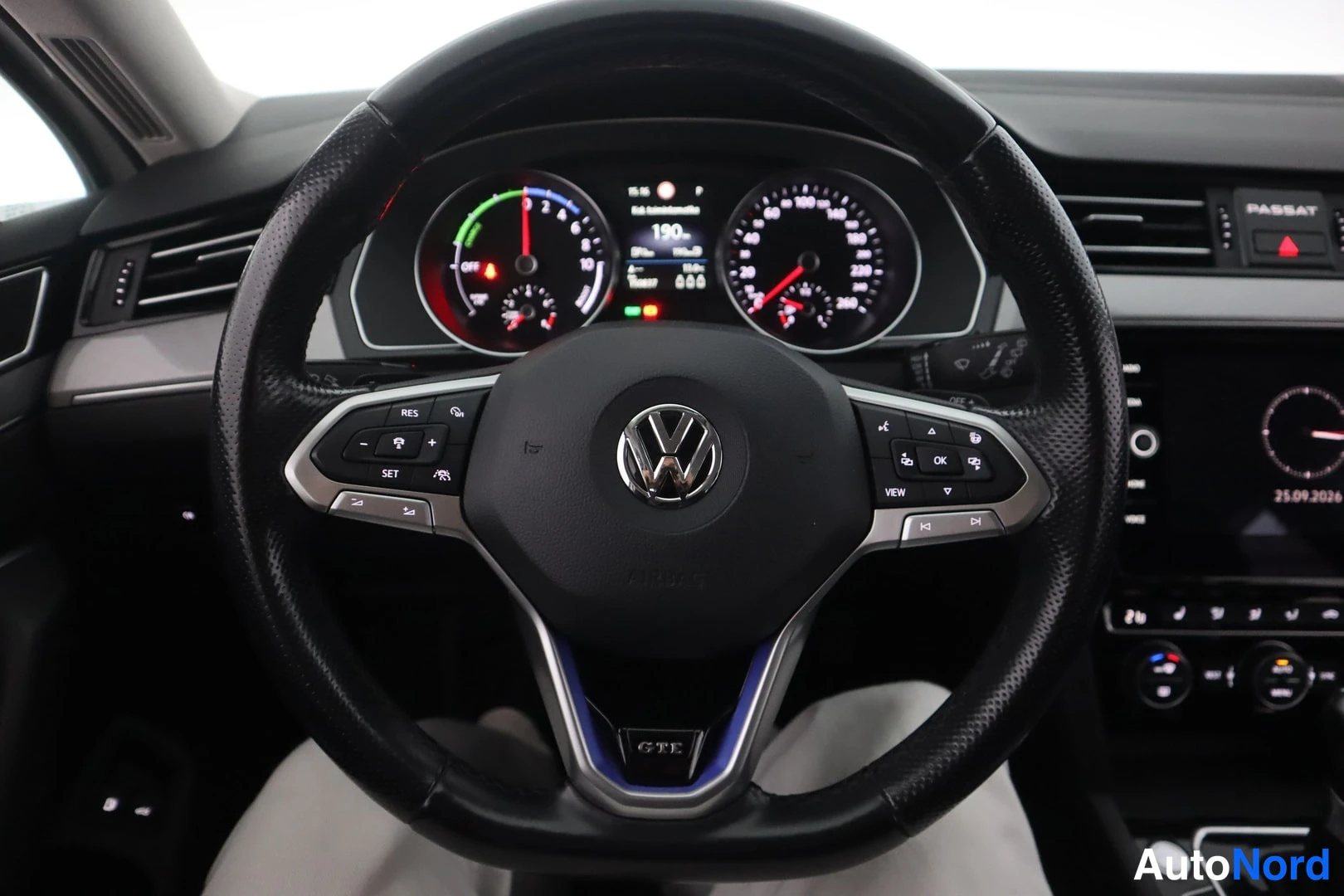 Yksityiskohta: Ohjauspyörän lähikuva: VW-logo, GTE-merkintä napakkaa ympäröivässä sinisessä koristeessa, digitaalinen mittaristo näkyvissä.