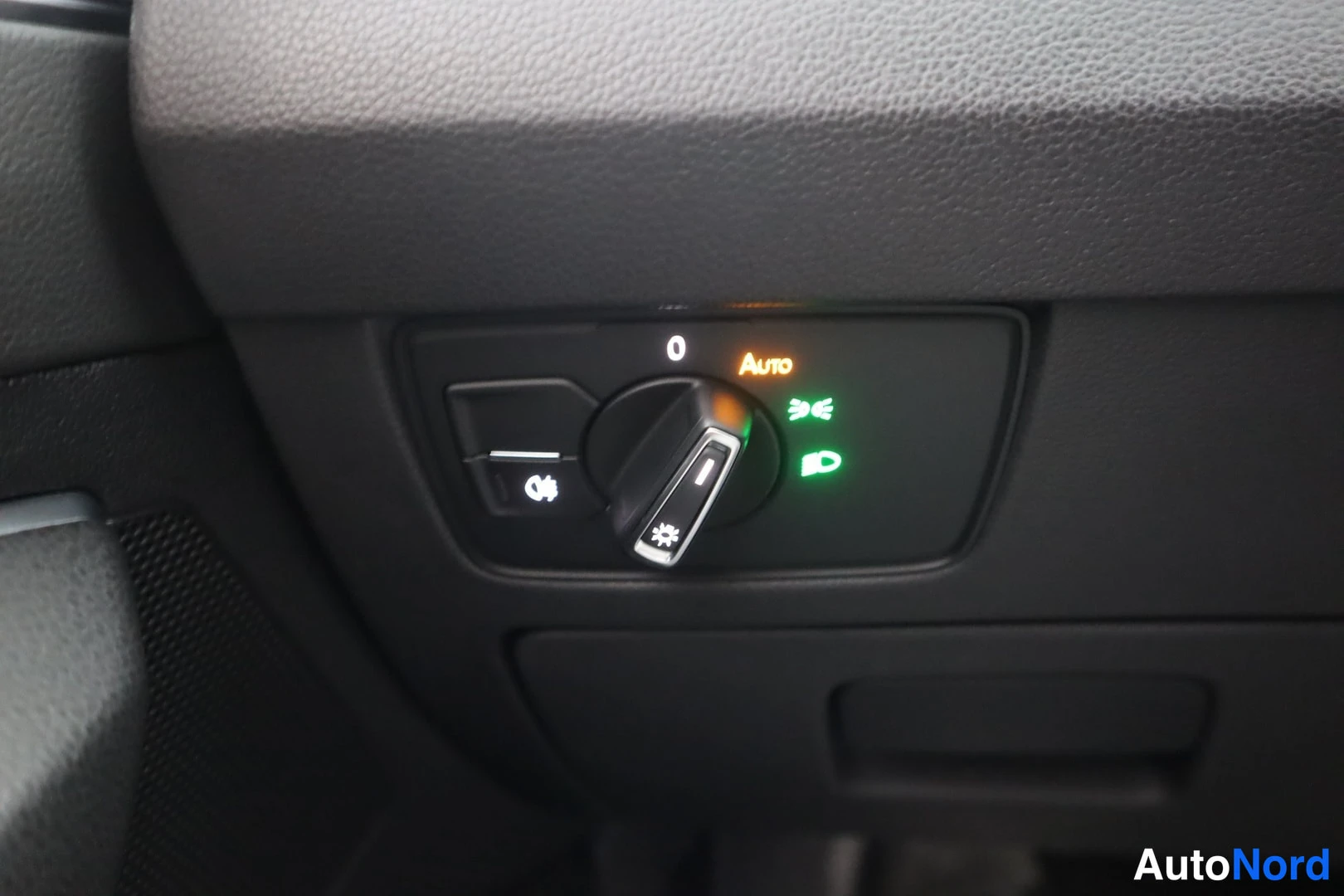 Muu: Sisätilakuva: kojelaudan valokytkin Auto-asennossa, vihreät sumuvalojen ja etuvalojen merkit valaistuna.